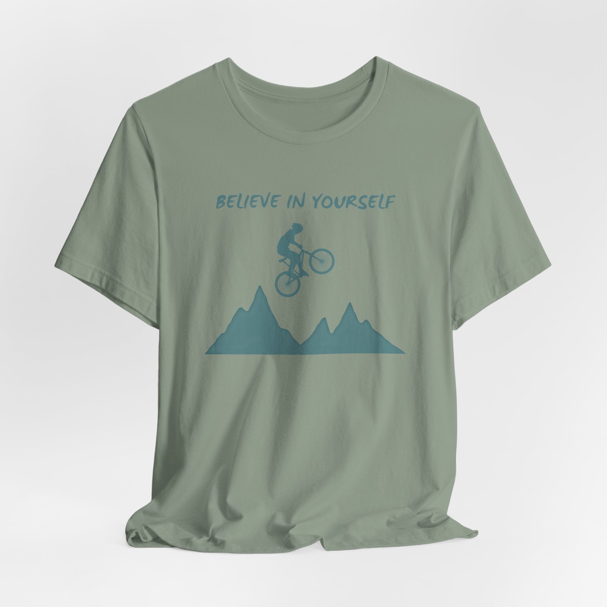 Sage green t-shirt with mountain bike graphic and 'Believe in Yourself' text on a white background