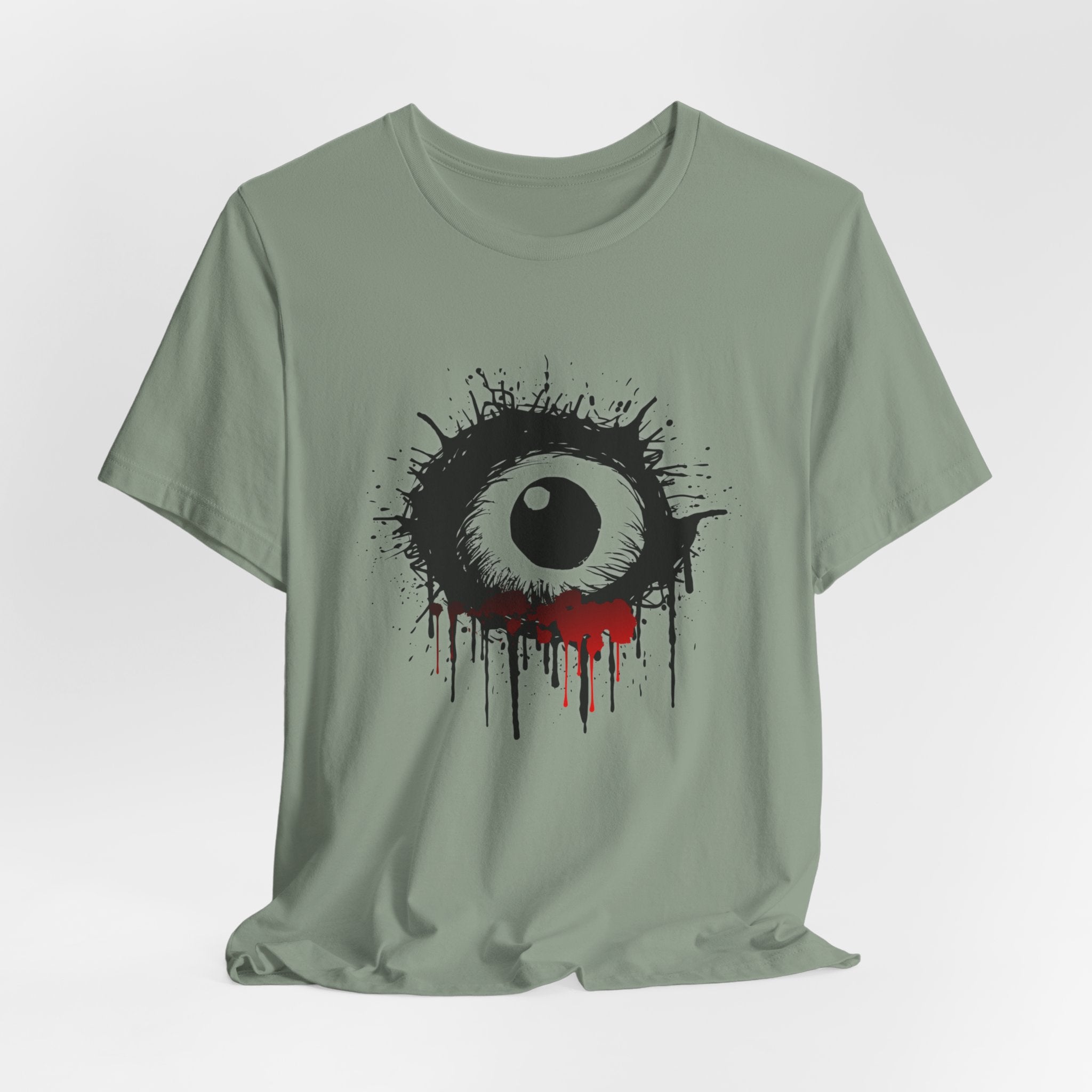 Sage green t-shirt with a black and white eye design on a light gray background