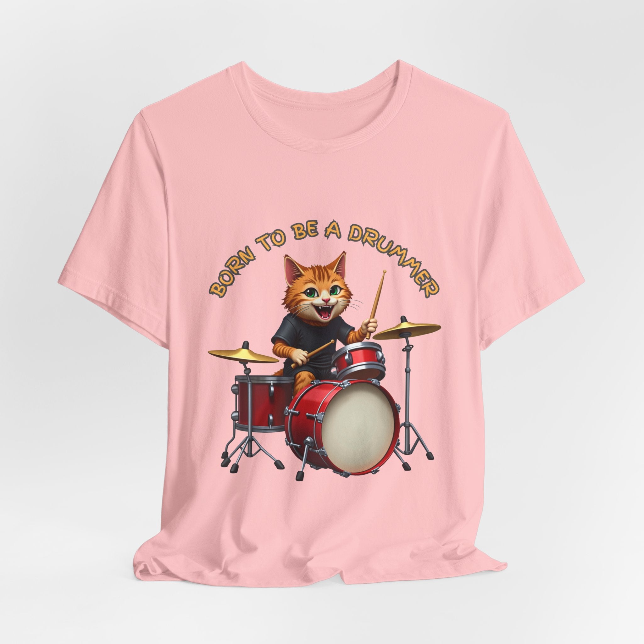Pink t-shirt with a cat playing drums graphic and 'Born to be a Drummer' text on a light gray background.