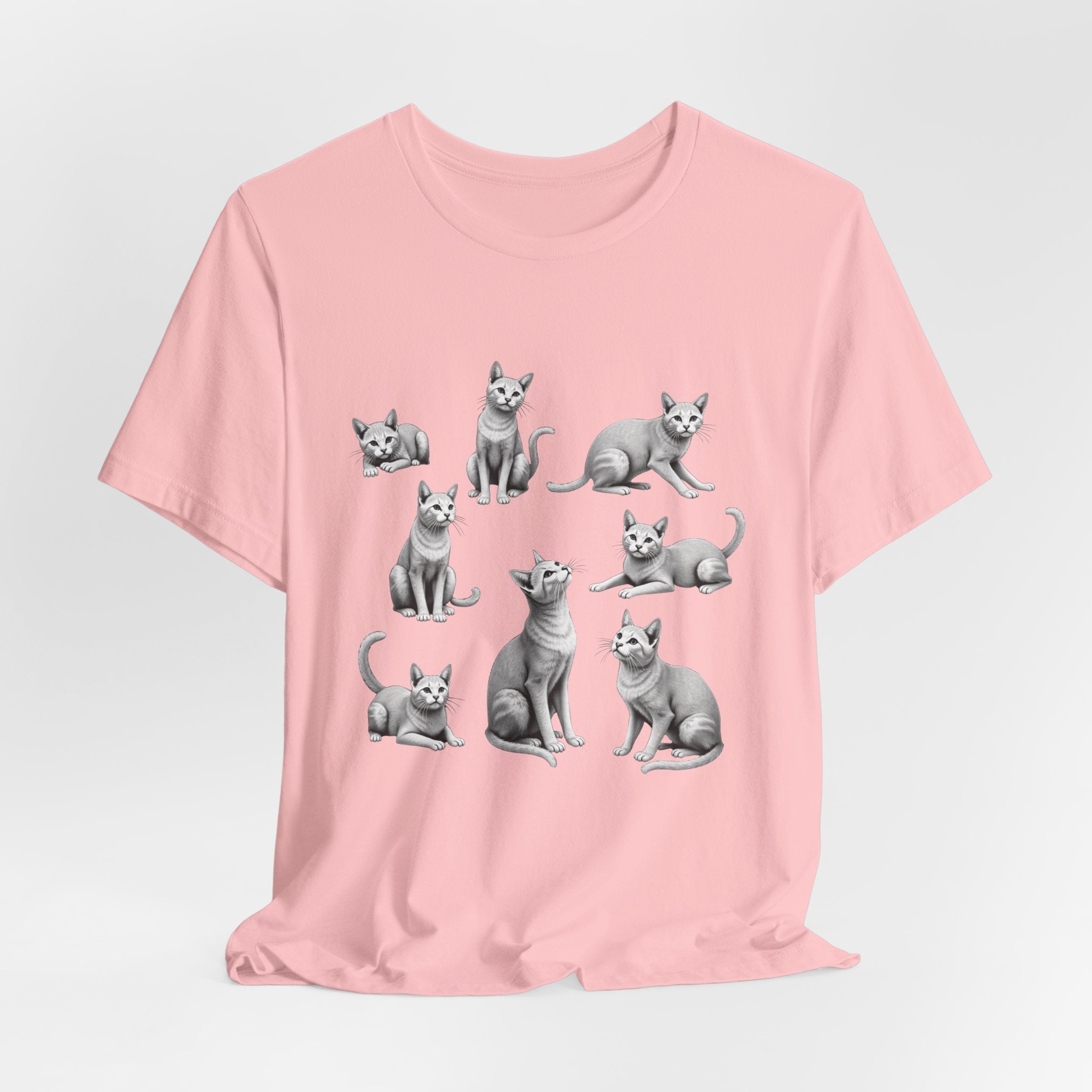 Pink t-shirt with gray cat illustrations on a light gray background