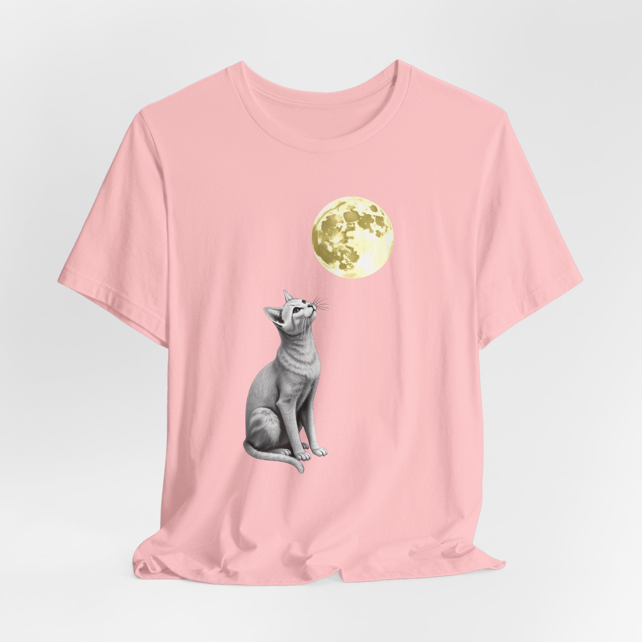 Pink t-shirt with a cat and moon graphic on a light gray background