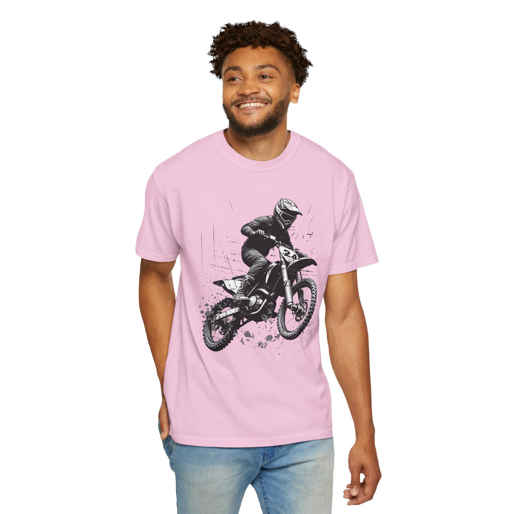 Man wearing a pink t-shirt with a graphic of a person on a motorcycle, standing against a white background.