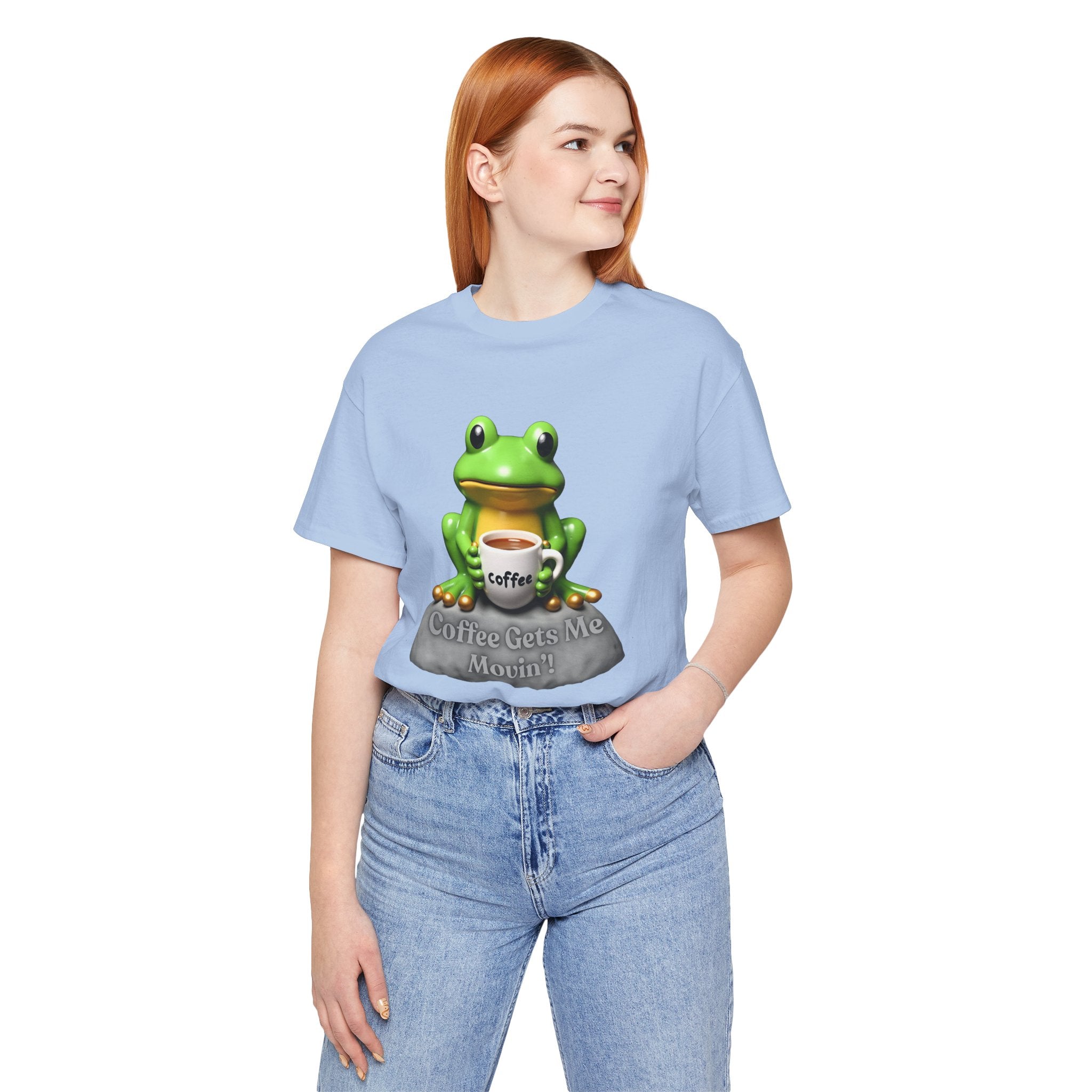 Person wearing a light blue t-shirt with a frog graphic and text, standing against a white background