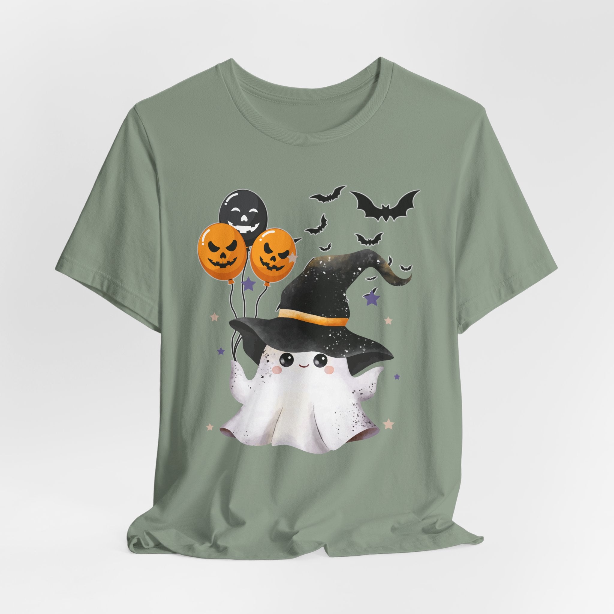 Sage green t-shirt with Halloween-themed design featuring a ghost, witch hat, and balloons on a white background.