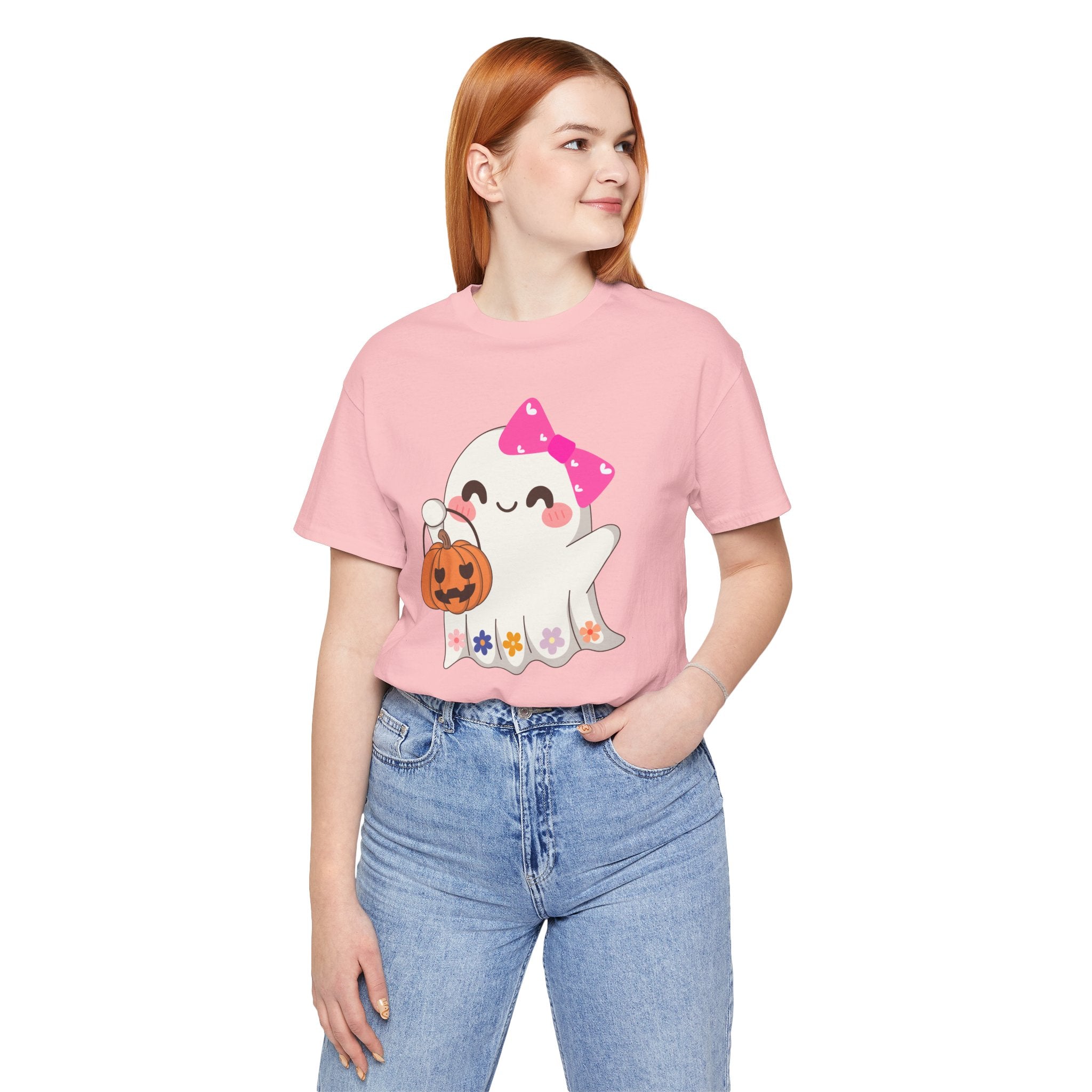 Person wearing a pink t-shirt with a ghost graphic and blue jeans on a white background