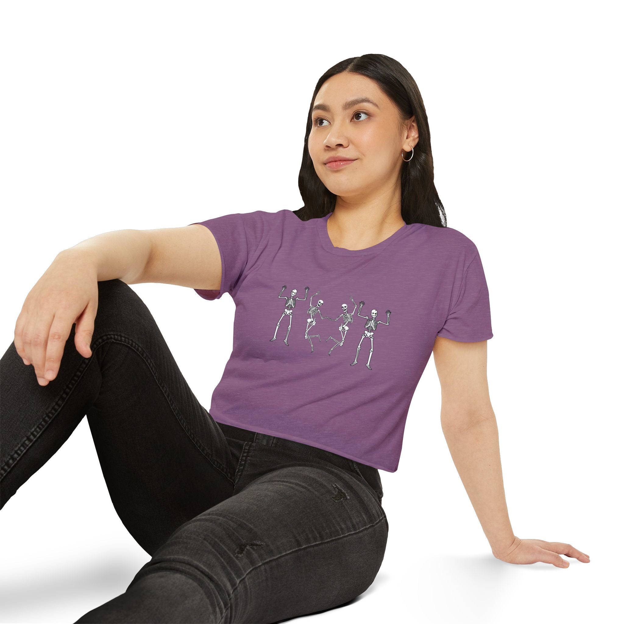 Woman wearing a purple t-shirt with skeleton designs sitting on a white background