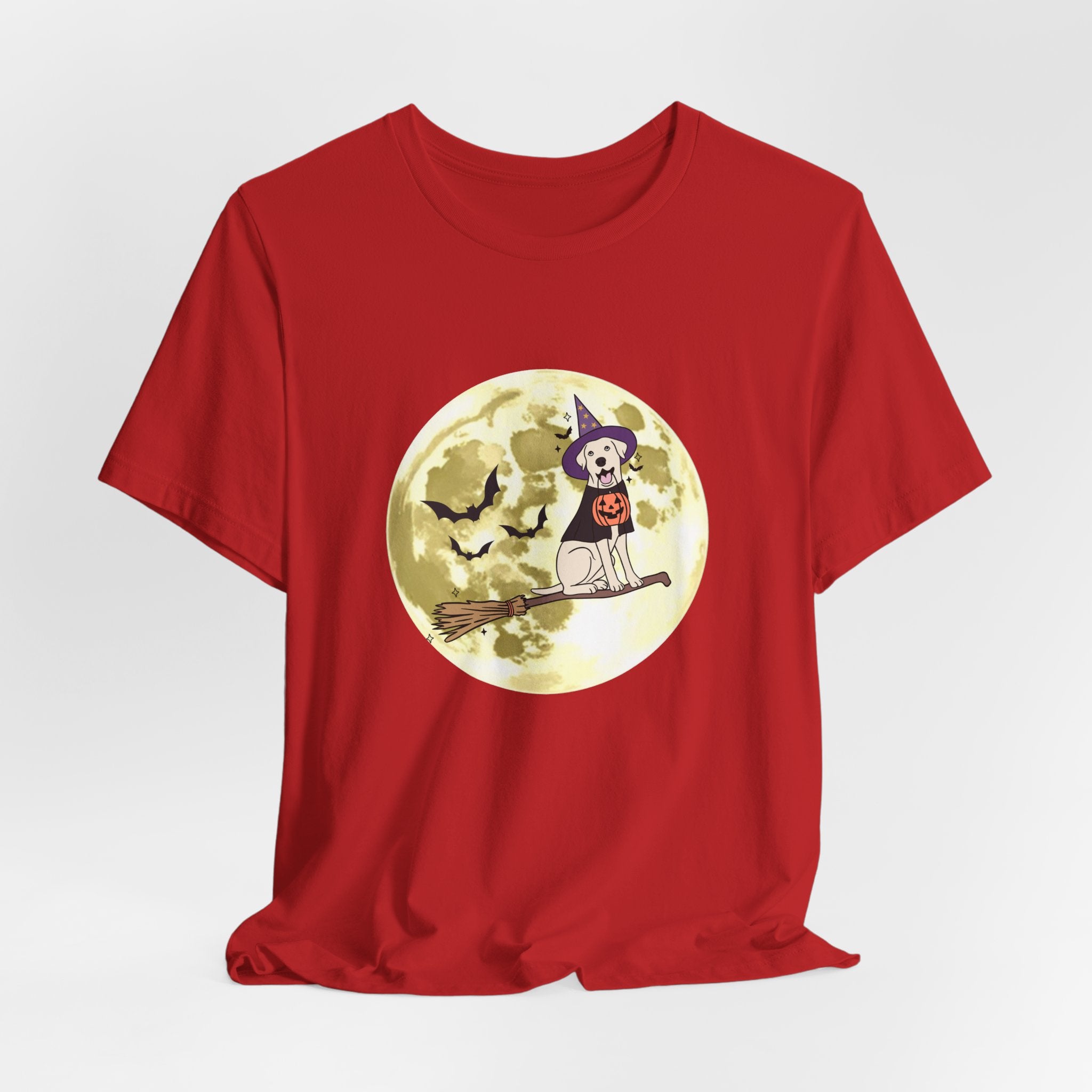 Red t-shirt with Halloween design featuring bats and a dog in a witch hat and pumpkin on a broomstick against a moonlit sky.