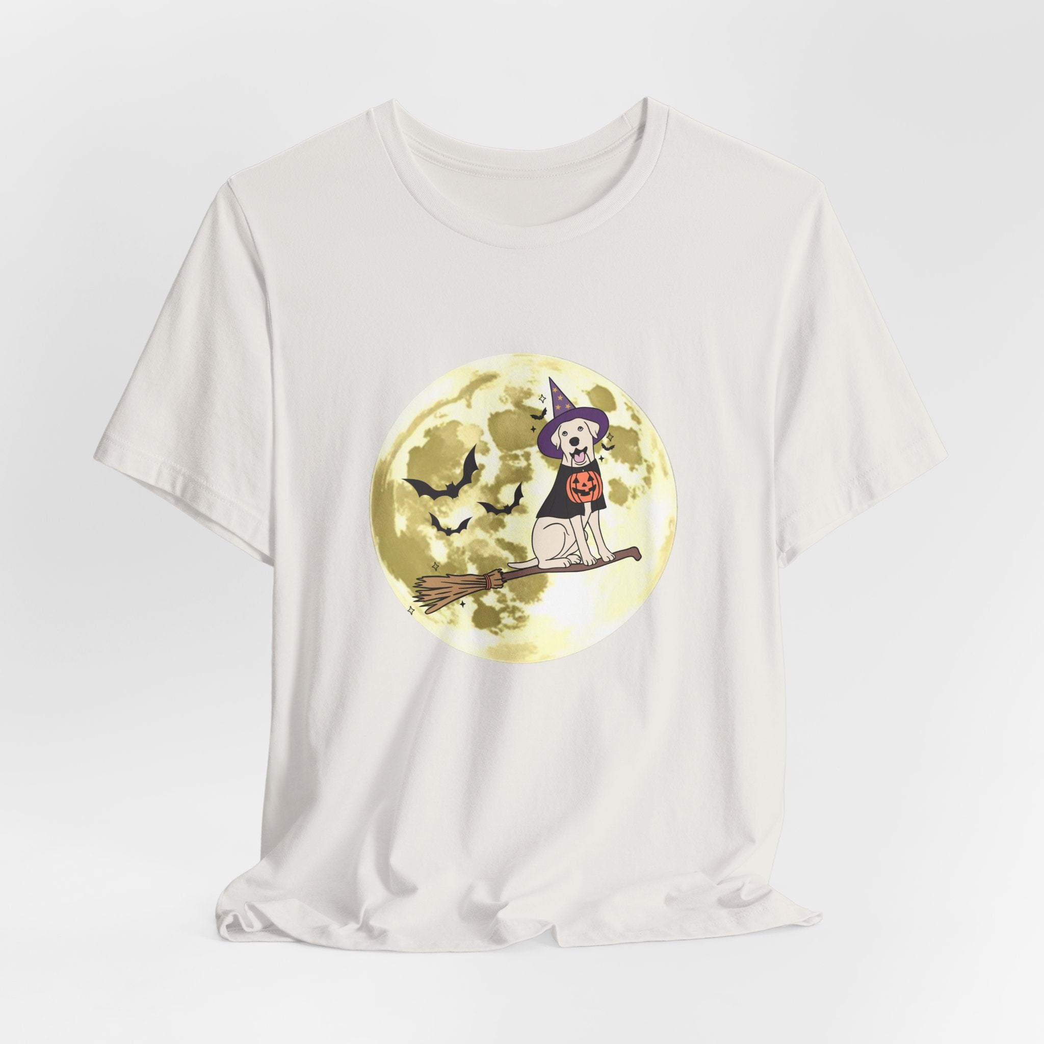 Vintage white t-shirt with Halloween design featuring bats and a dog in a witch hat and pumpkin on a broomstick against a moonlit sky.