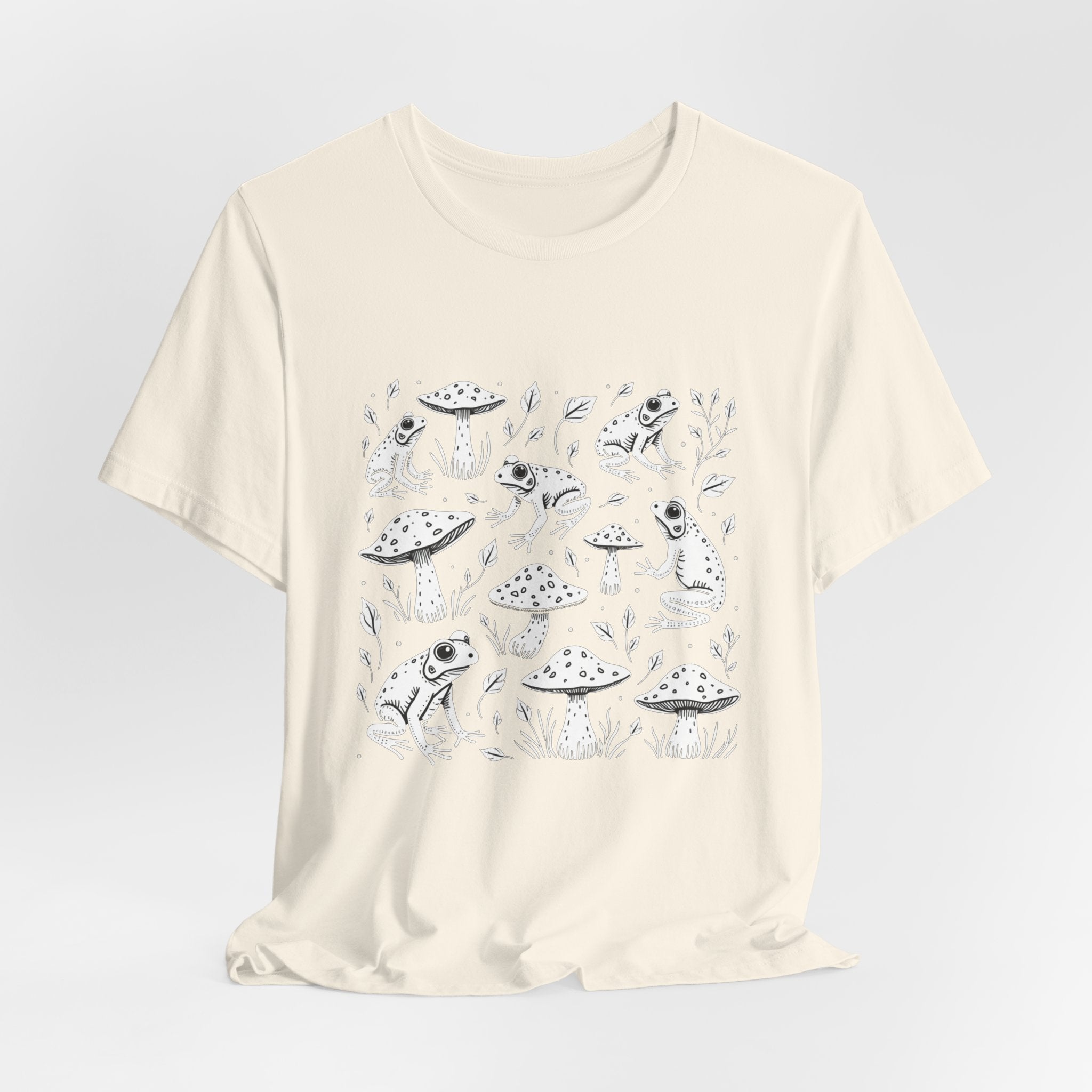 Ivory beige t-shirt with white frogs, grass and mushroom design on a white background