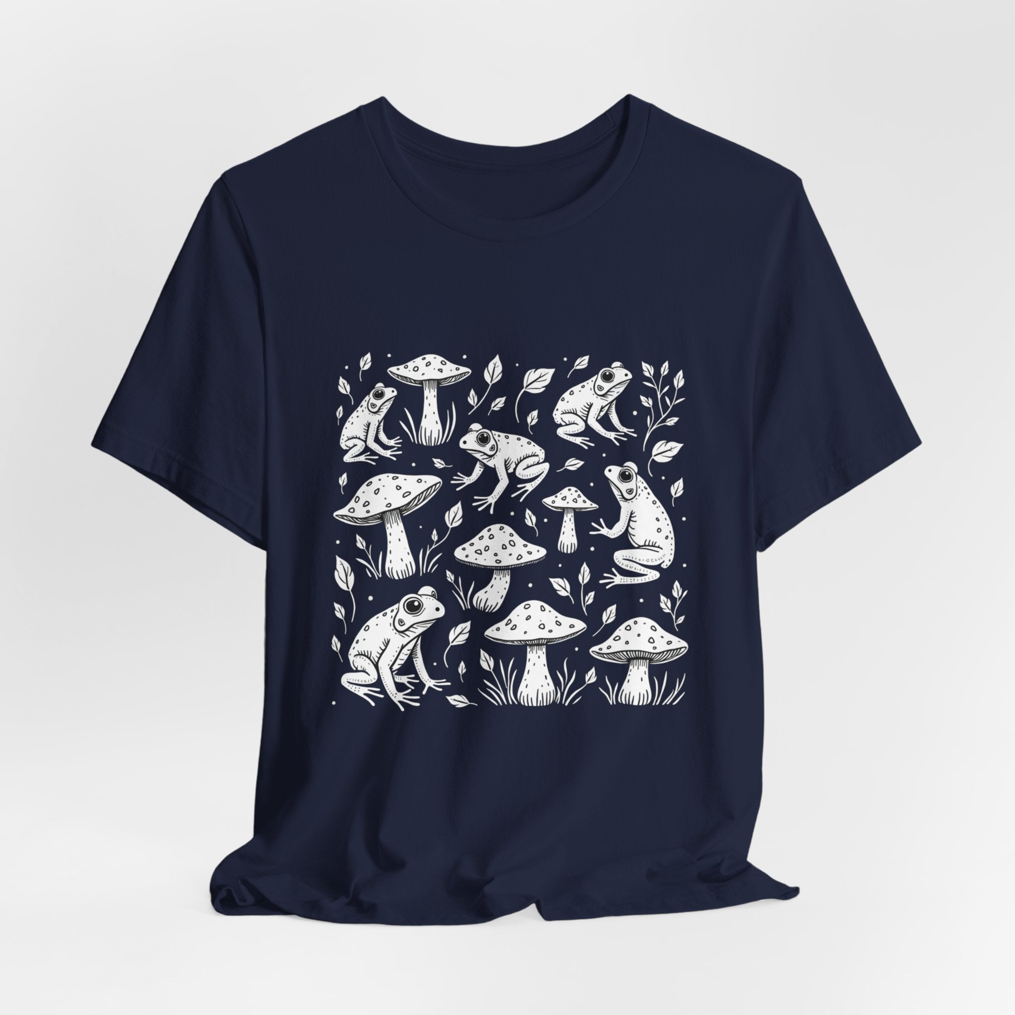 Navy blue t-shirt with white frogs, grass and mushroom design on a white background