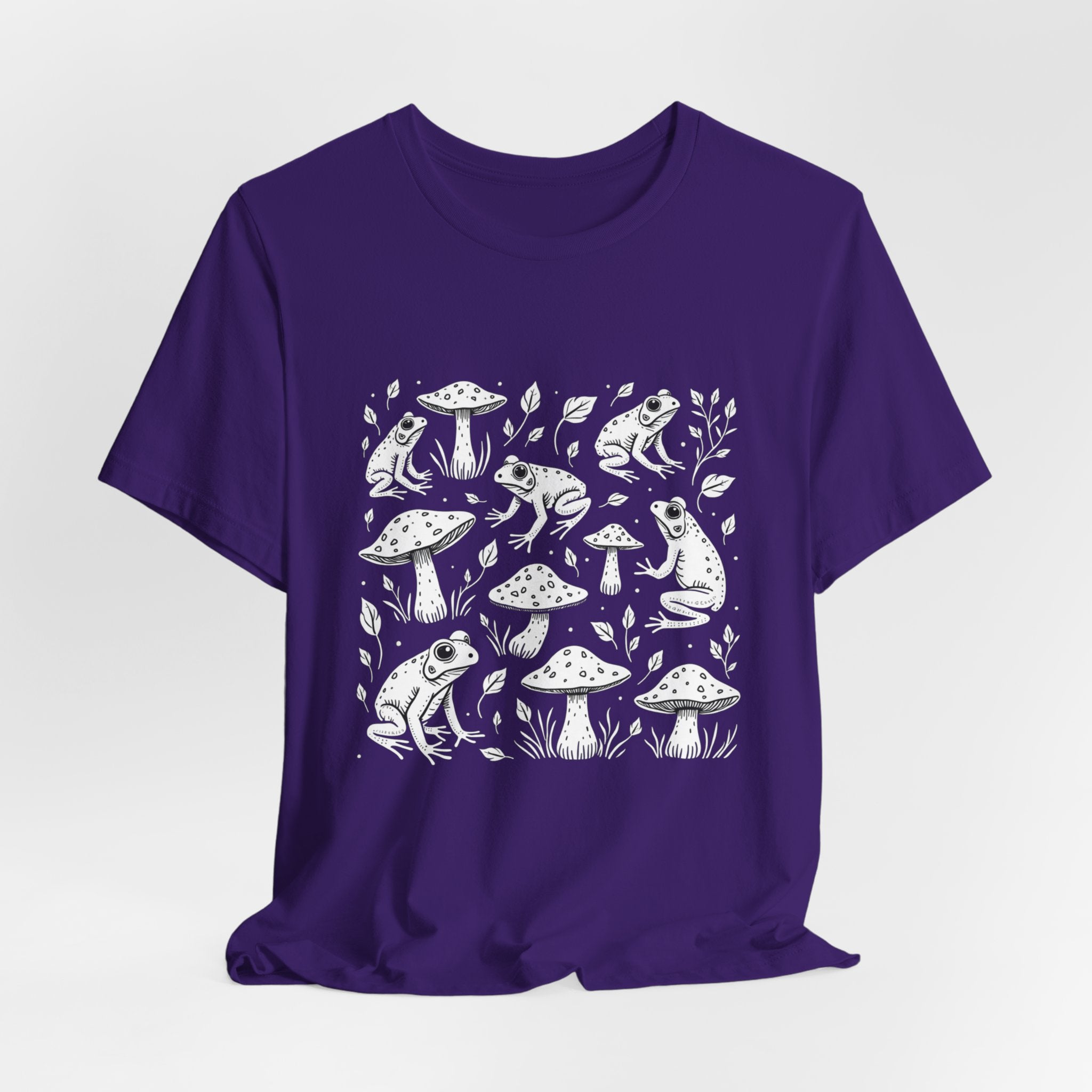 Team purple t-shirt with white frogs, grass and mushroom design on a white background