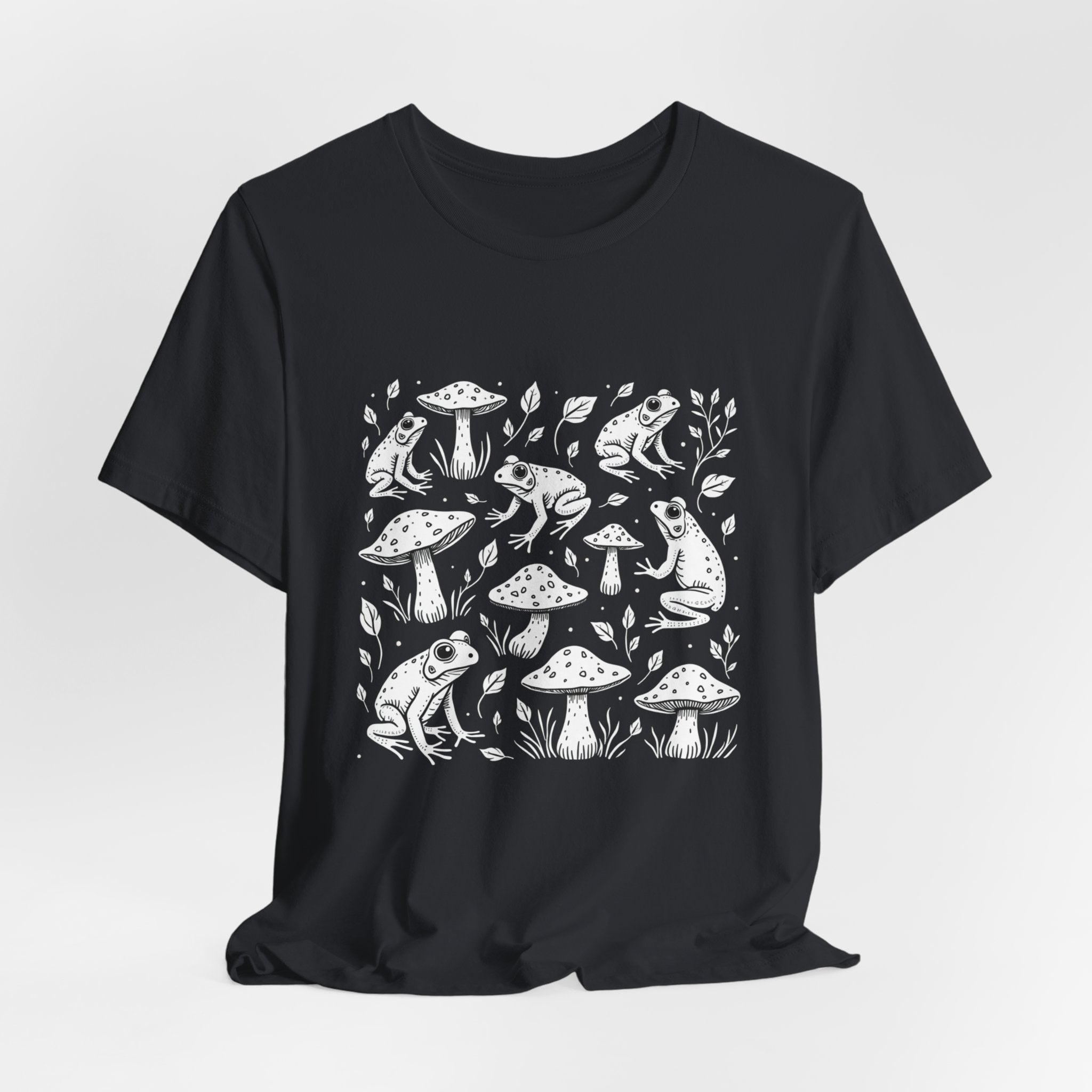 Vintage black t-shirt with white frogs, grass and mushroom design on a white background