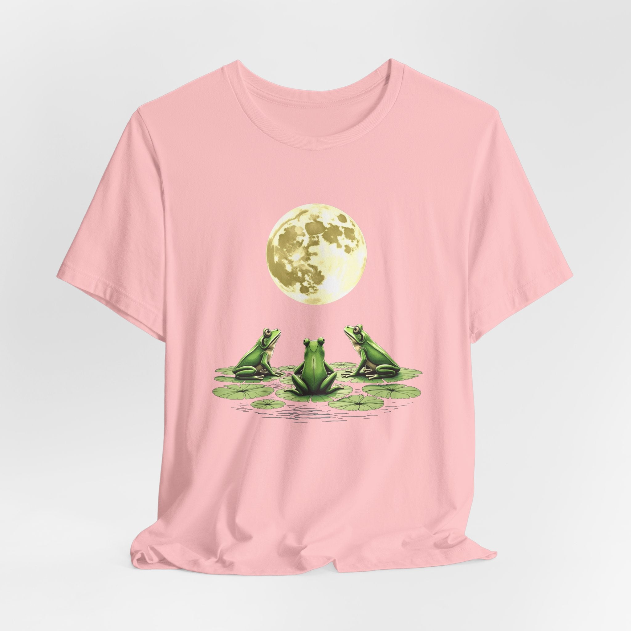 Pink t-shirt featuring cute frogs sitting on top of water lily watching on the moon graphic on a white background
