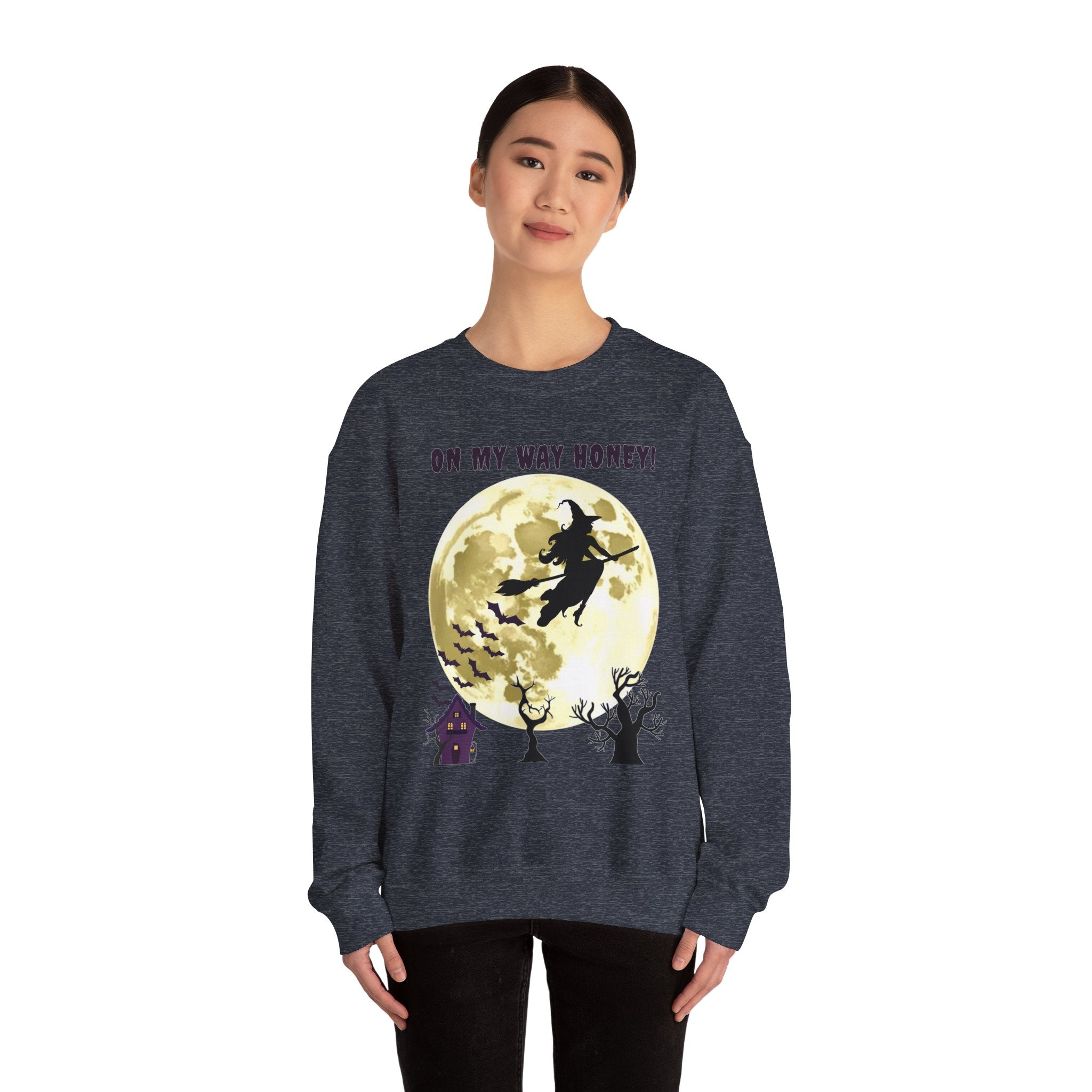 Person wearing a dark blue sweatshirt with a Halloween design featuring a witch on a broomstick over a full moon.