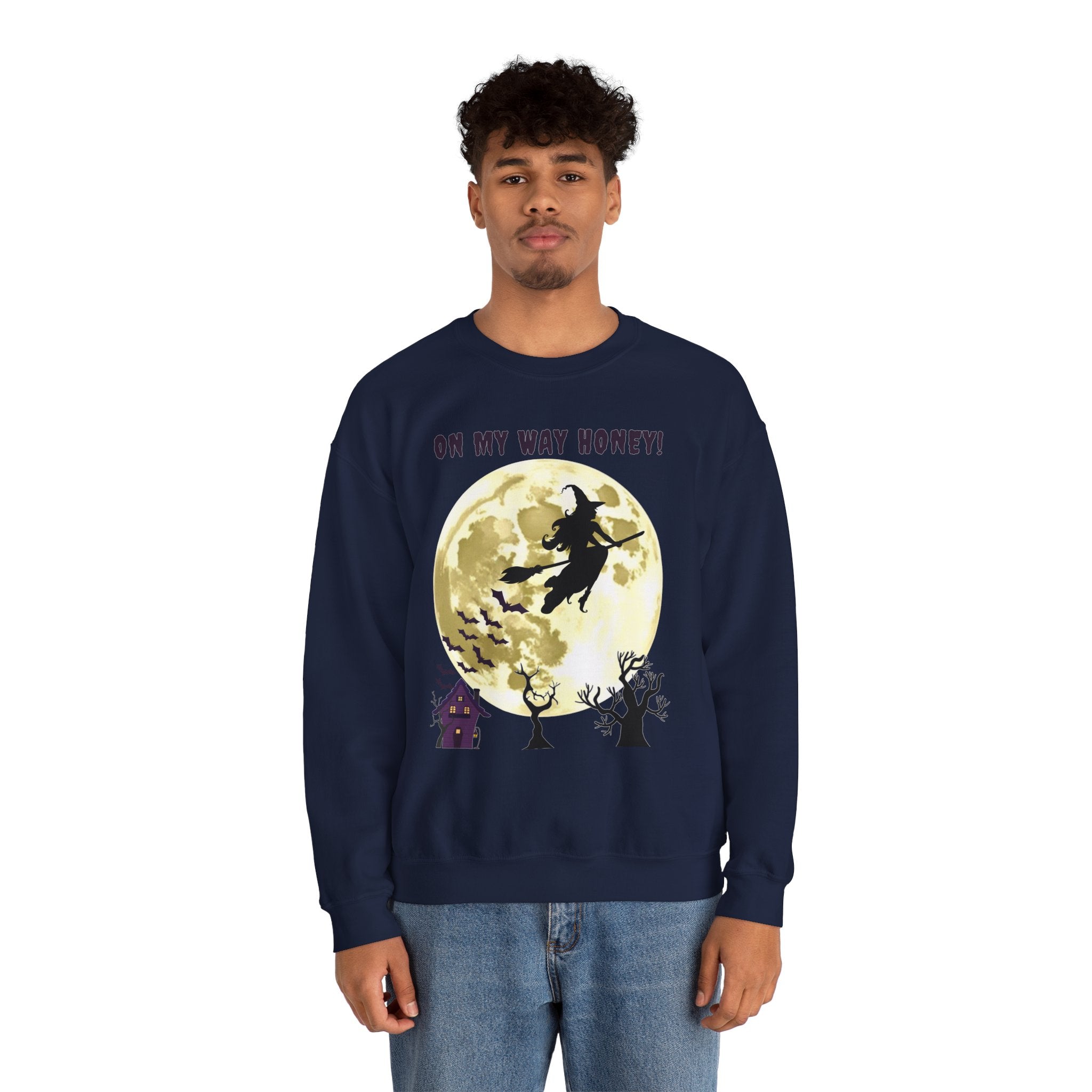 Person wearing a navy sweatshirt with a Halloween design featuring a witch on a broomstick over a full moon.