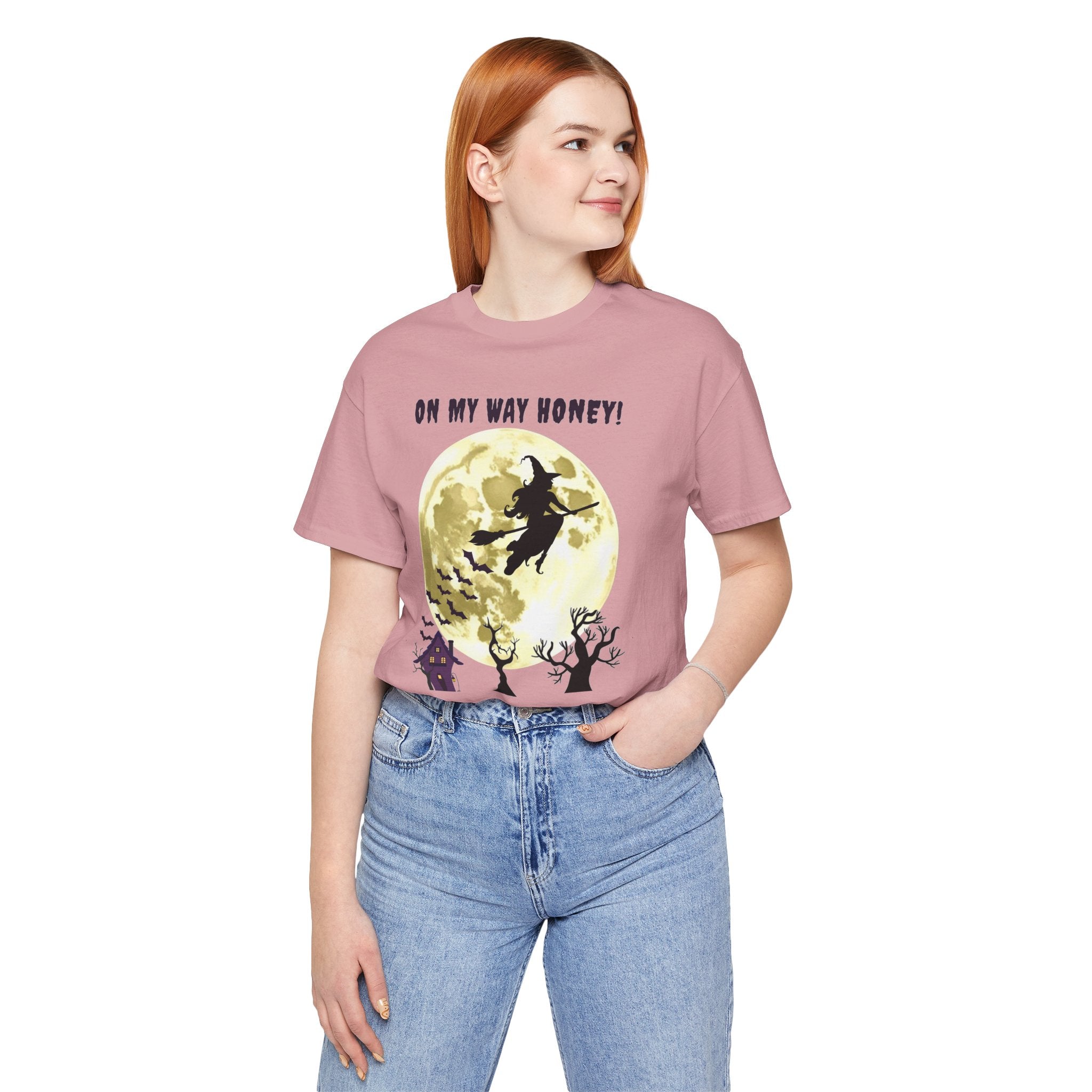 Person wearing a pink t-shirt with a graphic design and text, standing against a white background