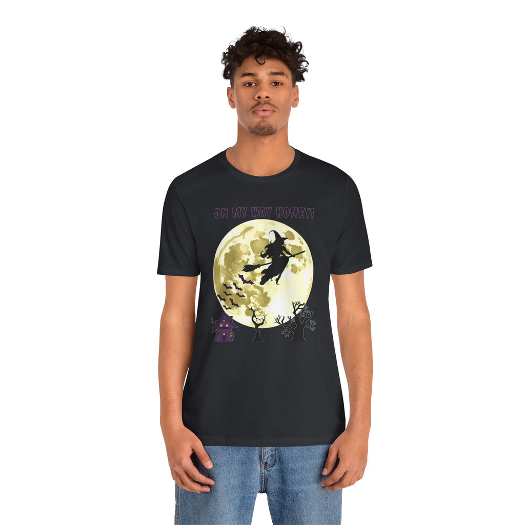 Person wearing a black t-shirt with a Halloween design featuring a witch on a broomstick against a moonlit sky.