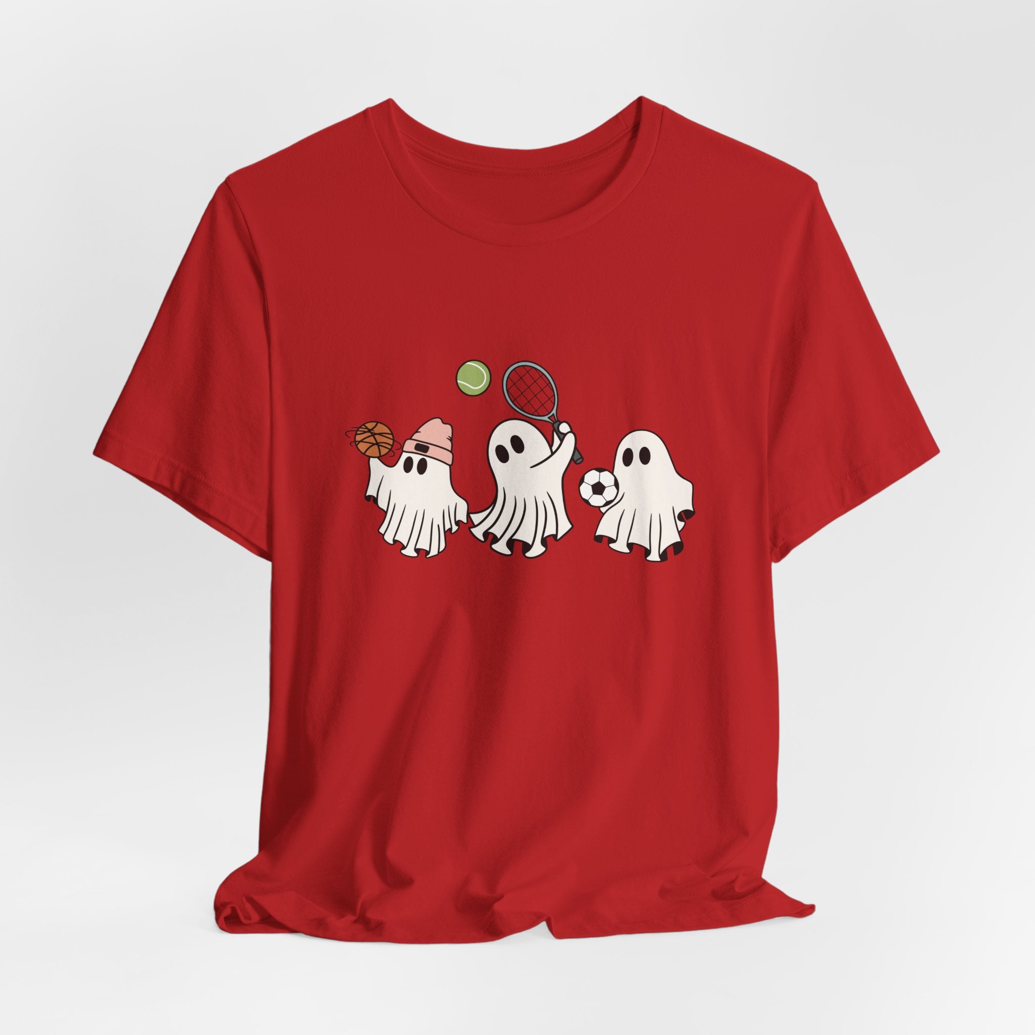Red t-shirt with cartoon halloween ghosts playing basketball, tennis, and football on a white background