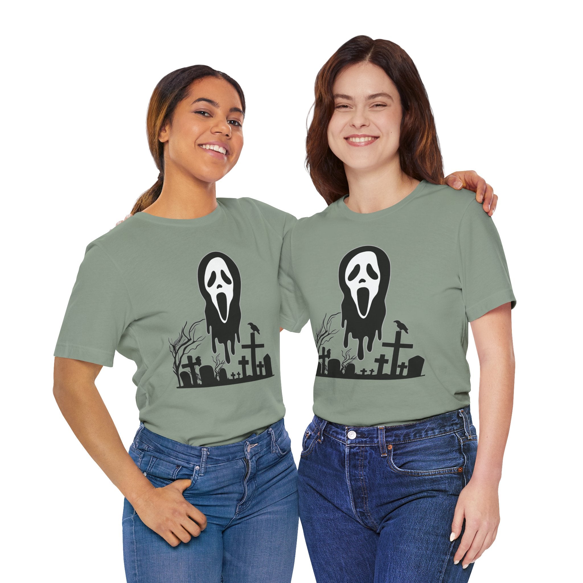 Two people wearing green t-shirts with a graphic design of a ghost face and cemetery.