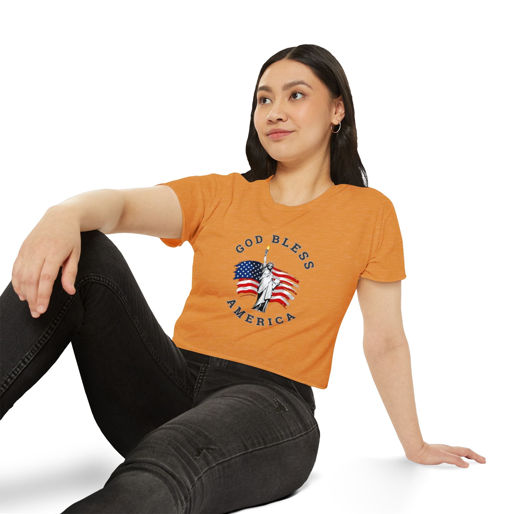 Woman wearing an orange t-shirt with a graphic design sitting on a white background