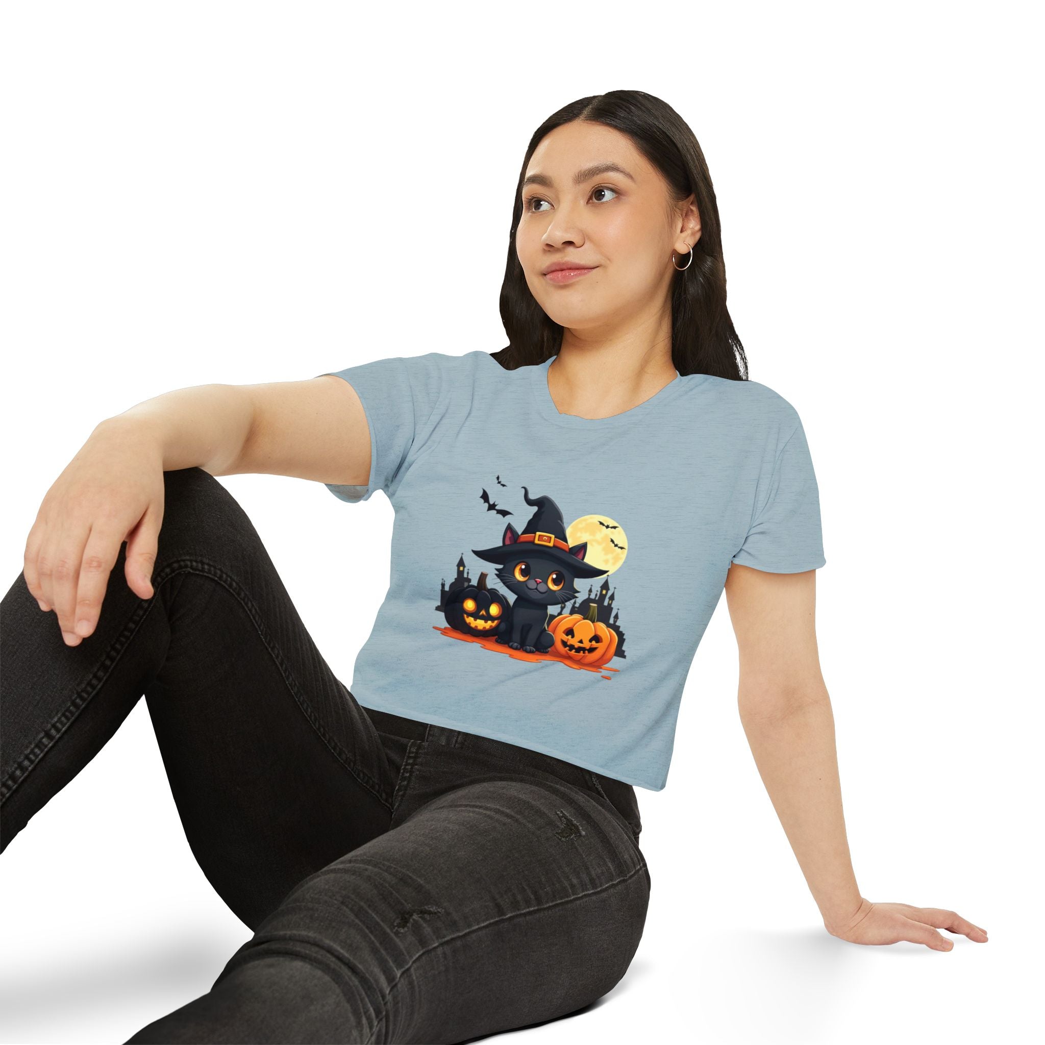 Woman wearing a light blue t-shirt with a Halloween design, sitting on a white background.