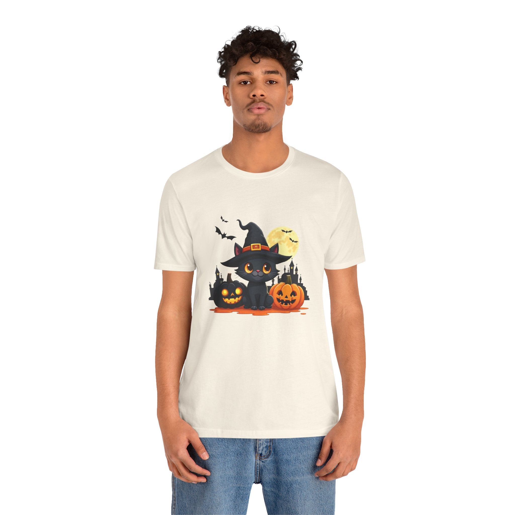 Person wearing a white t-shirt with a Halloween-themed design featuring a black cat, jack-o'-lantern, and witch hat.