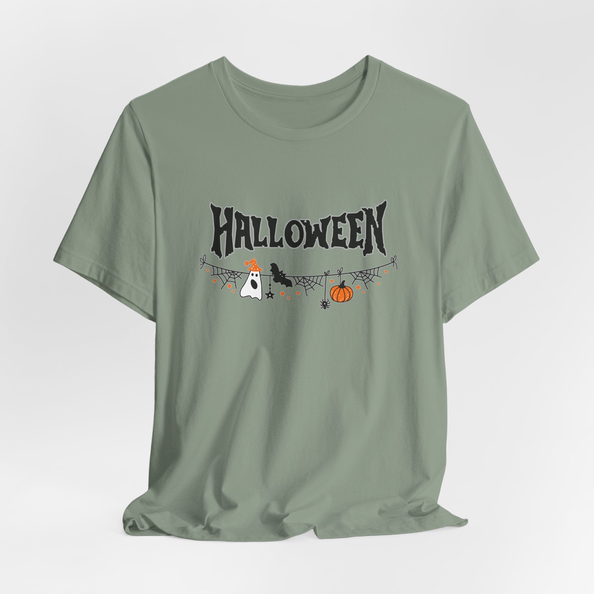 Sage green t-shirt with Halloween-themed graphics on a light gray background