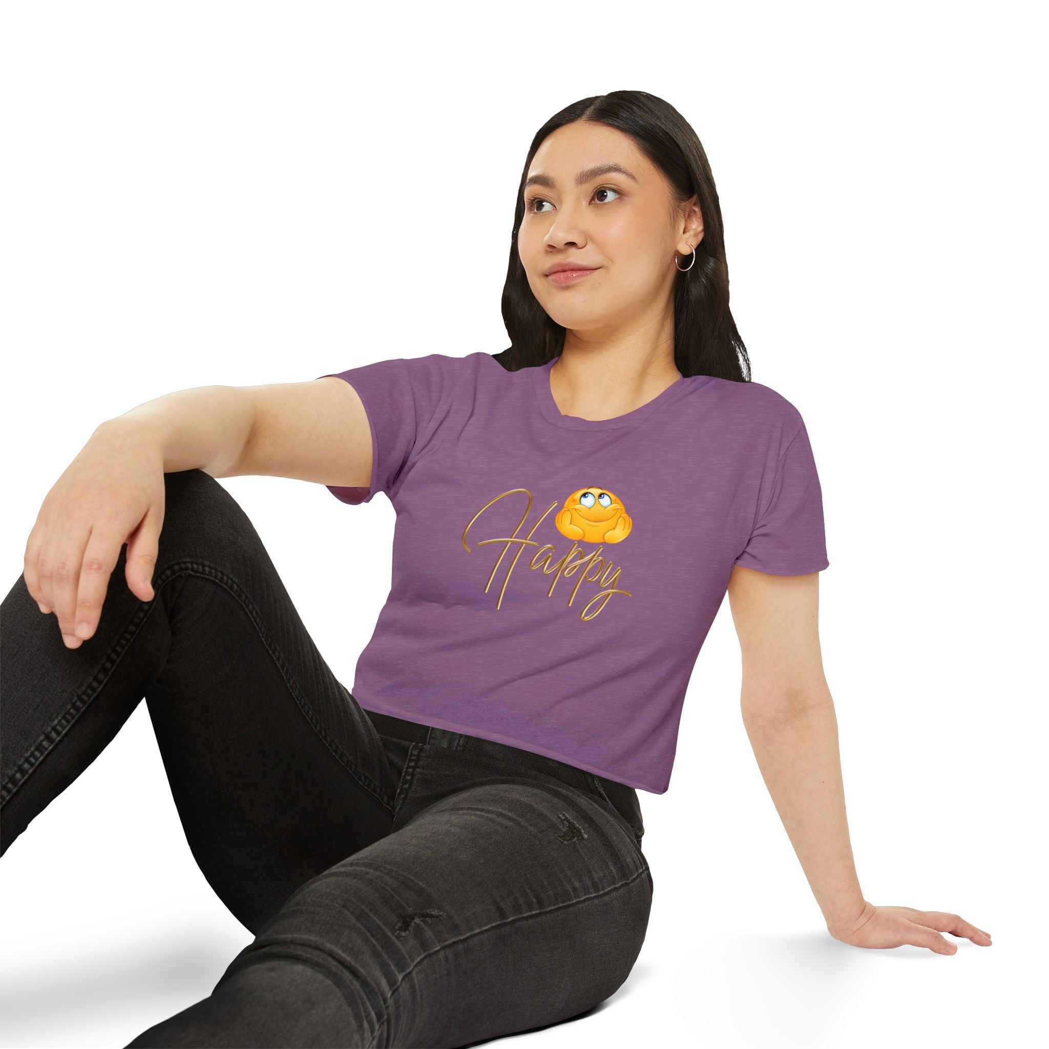 Woman wearing a white crop top t-shirt with a graphic design of happy emoji, sitting on a white background.