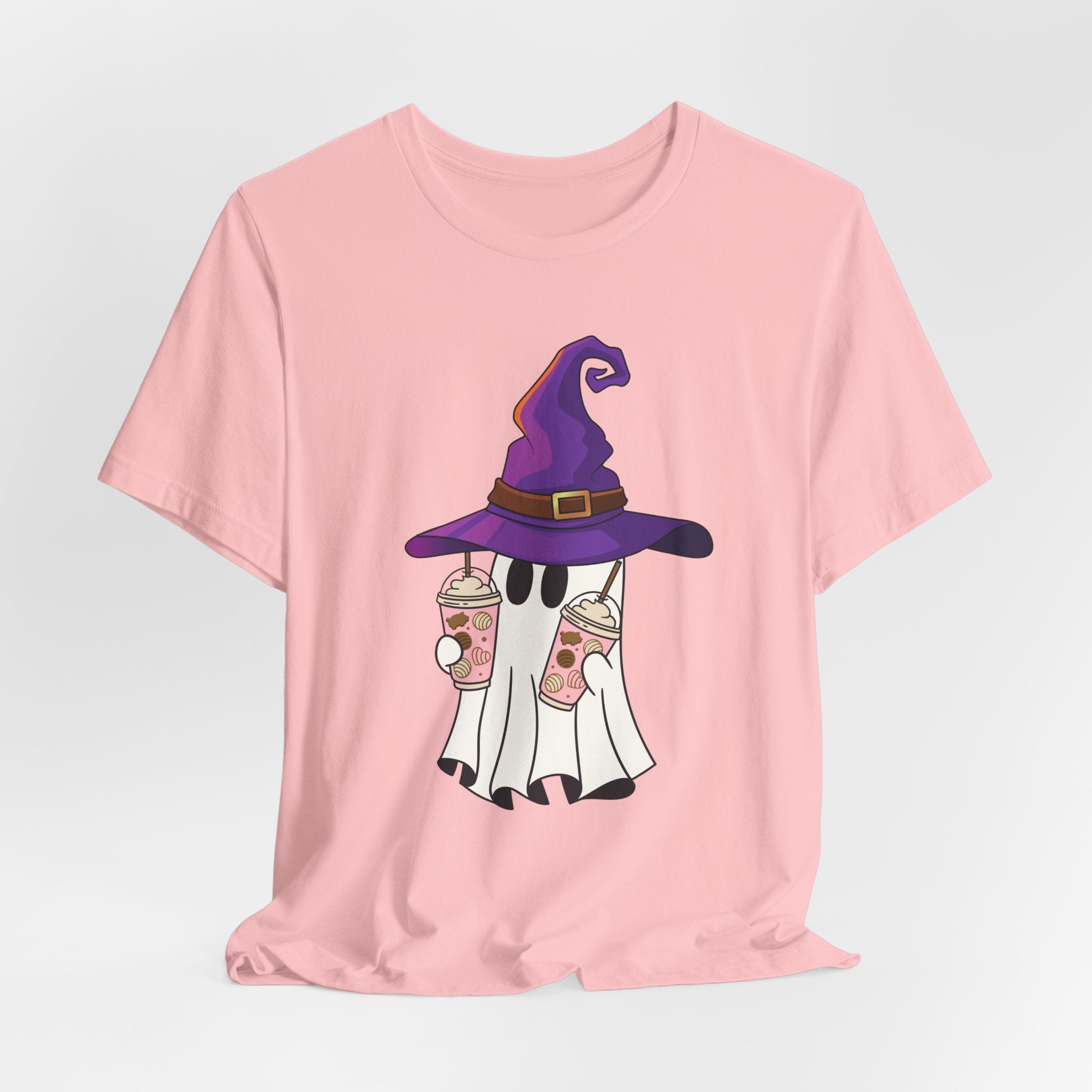 Pink t-shirt with ghost and purple witch hat graphic holding two cups of  juice on a light gray background 