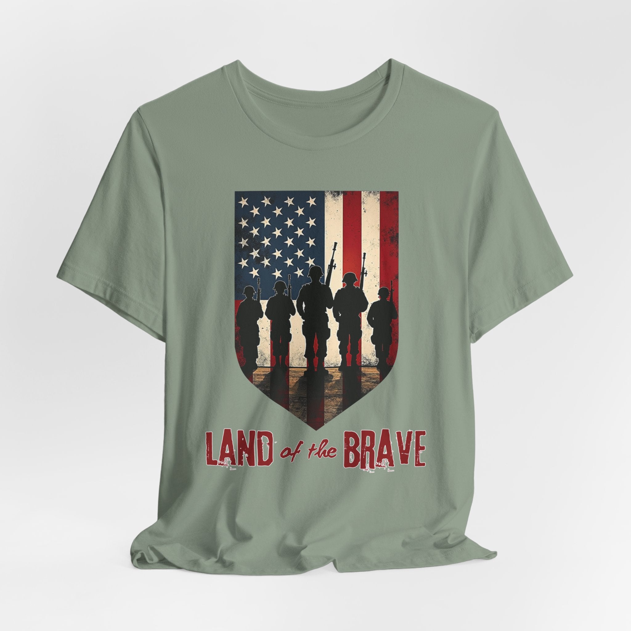Sage green t-shirt with vintage American flag, soldiers, and silhouette design with land of the brave text on a white background