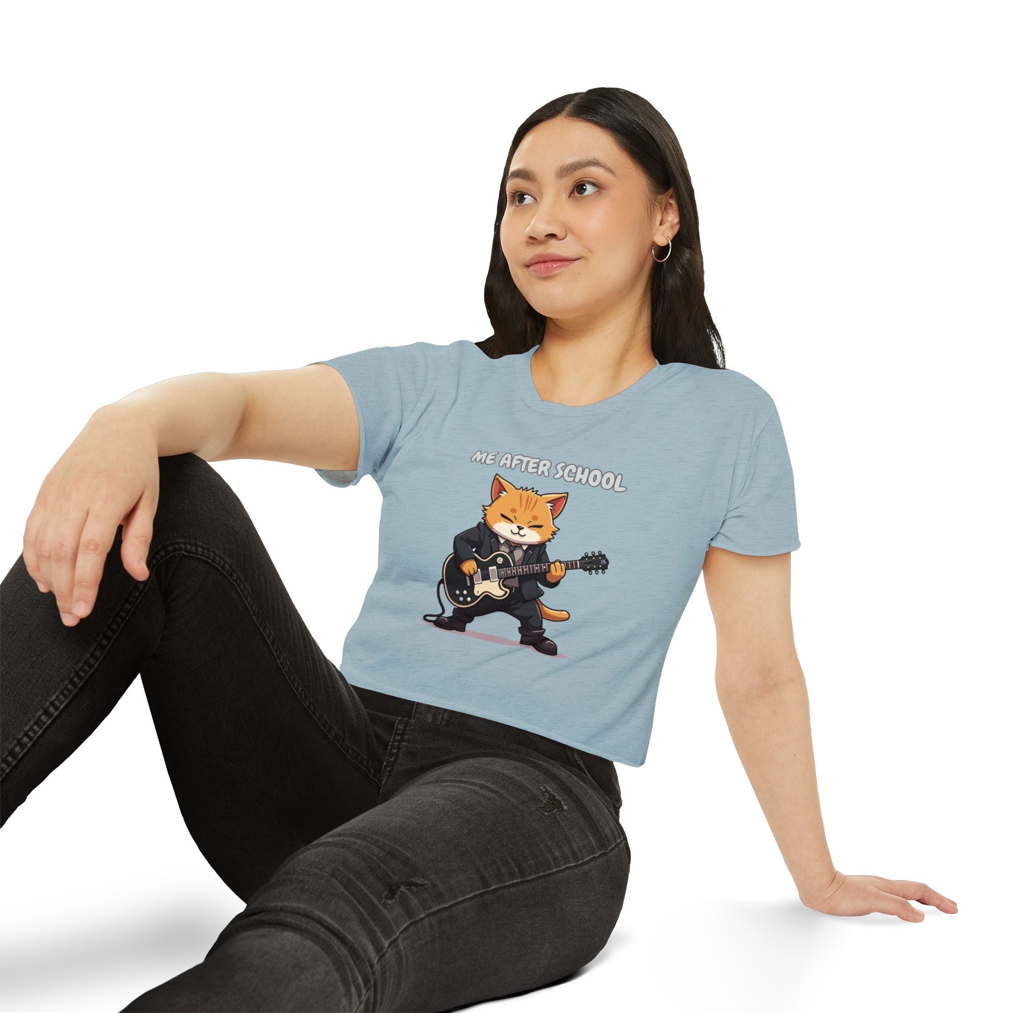Woman wearing a light blue t-shirt with a graphic of a cat playing guitar and the text 'The After School'.