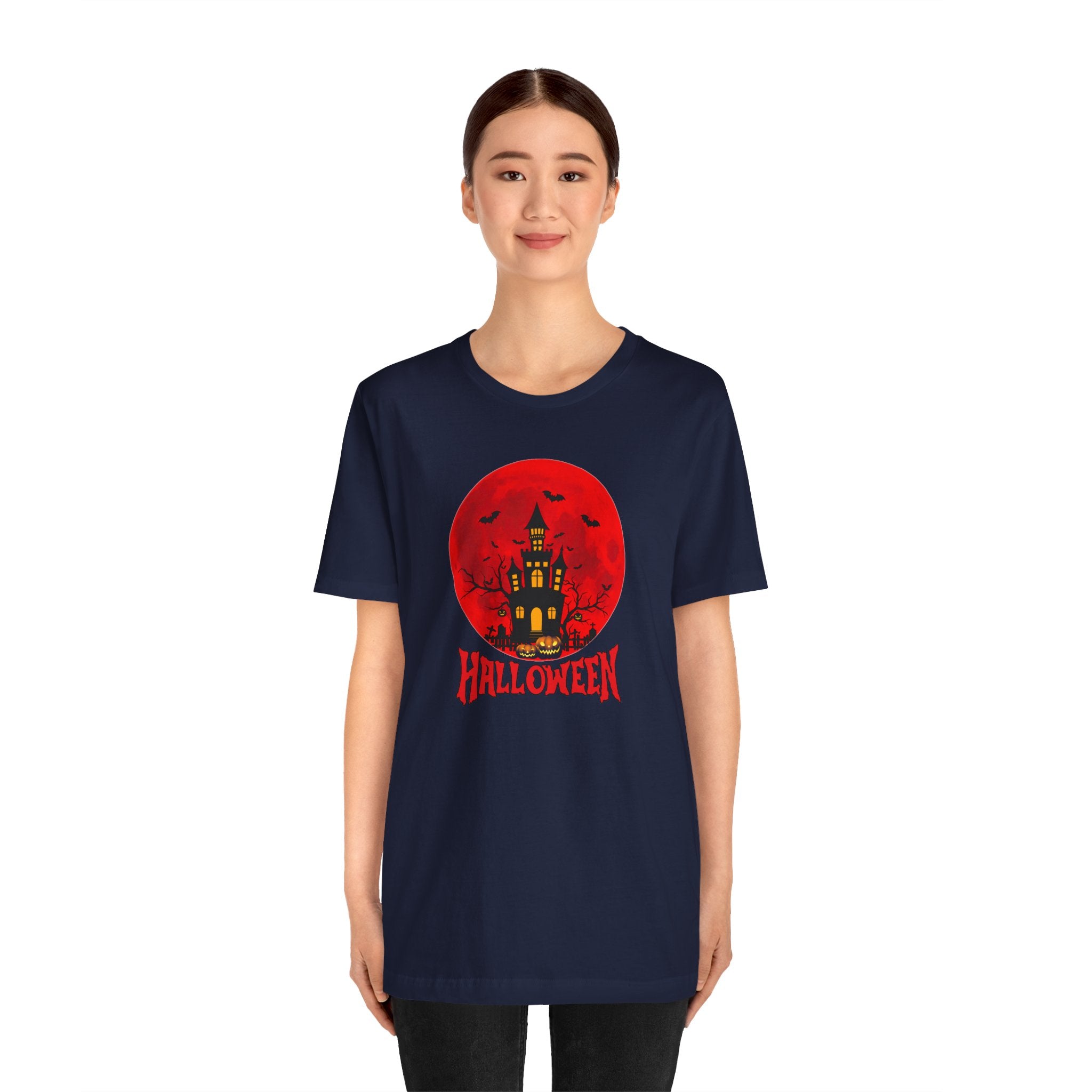 Person wearing a navy blue t-shirt with a Halloween design featuring a red moon and castle.