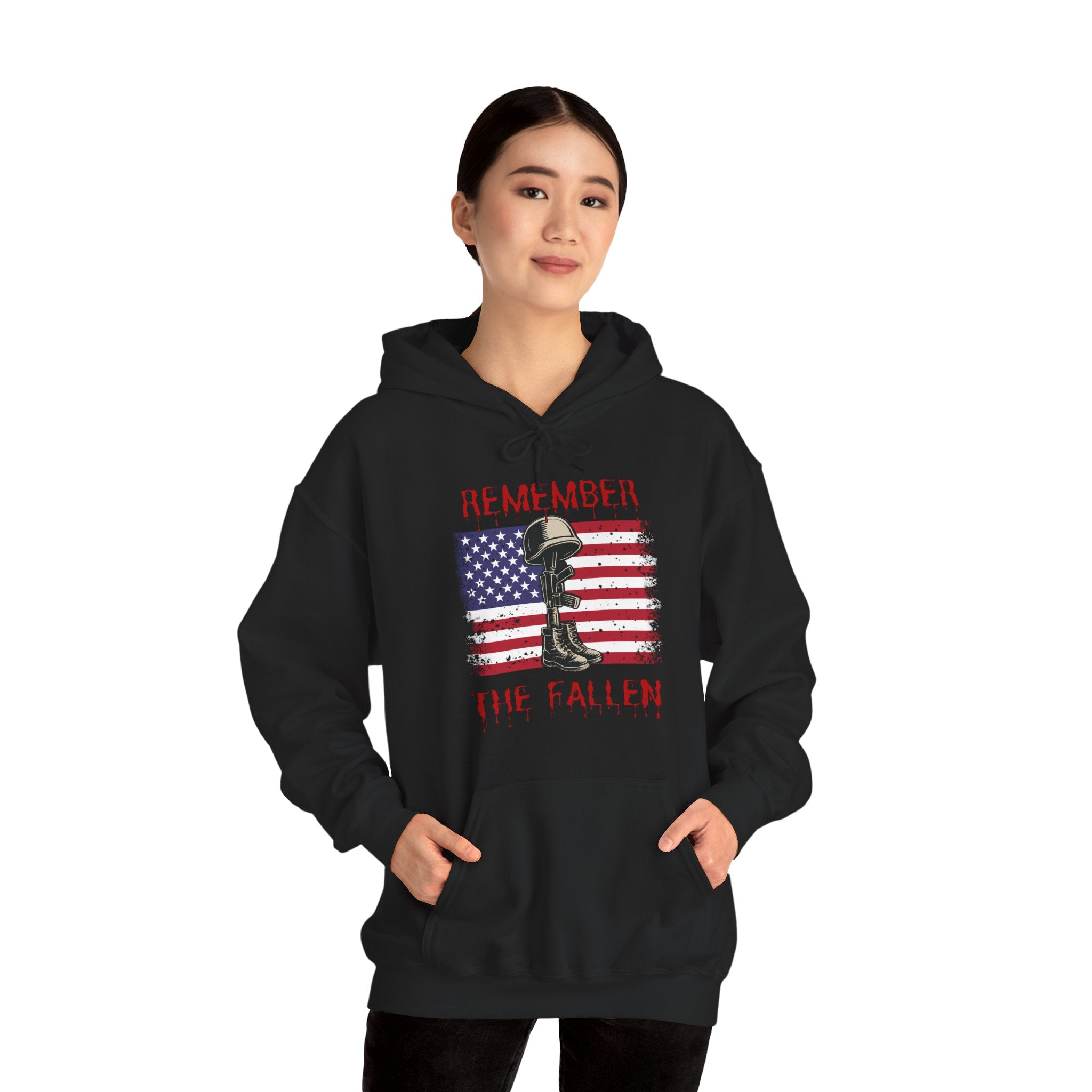 Person wearing a black hoodie with a graphic design of vintage American flag with soldiers gear and "Remember the Fallen" text on a white background