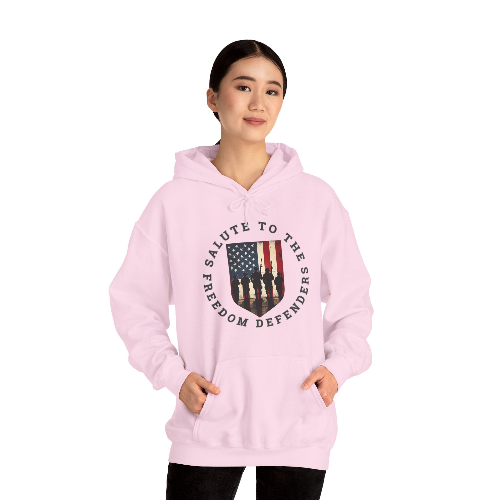 Person wearing a pink hoodie with a graphic design of vintage USA flag with soldiers and "salute to the freedom defenders" text on a white background
