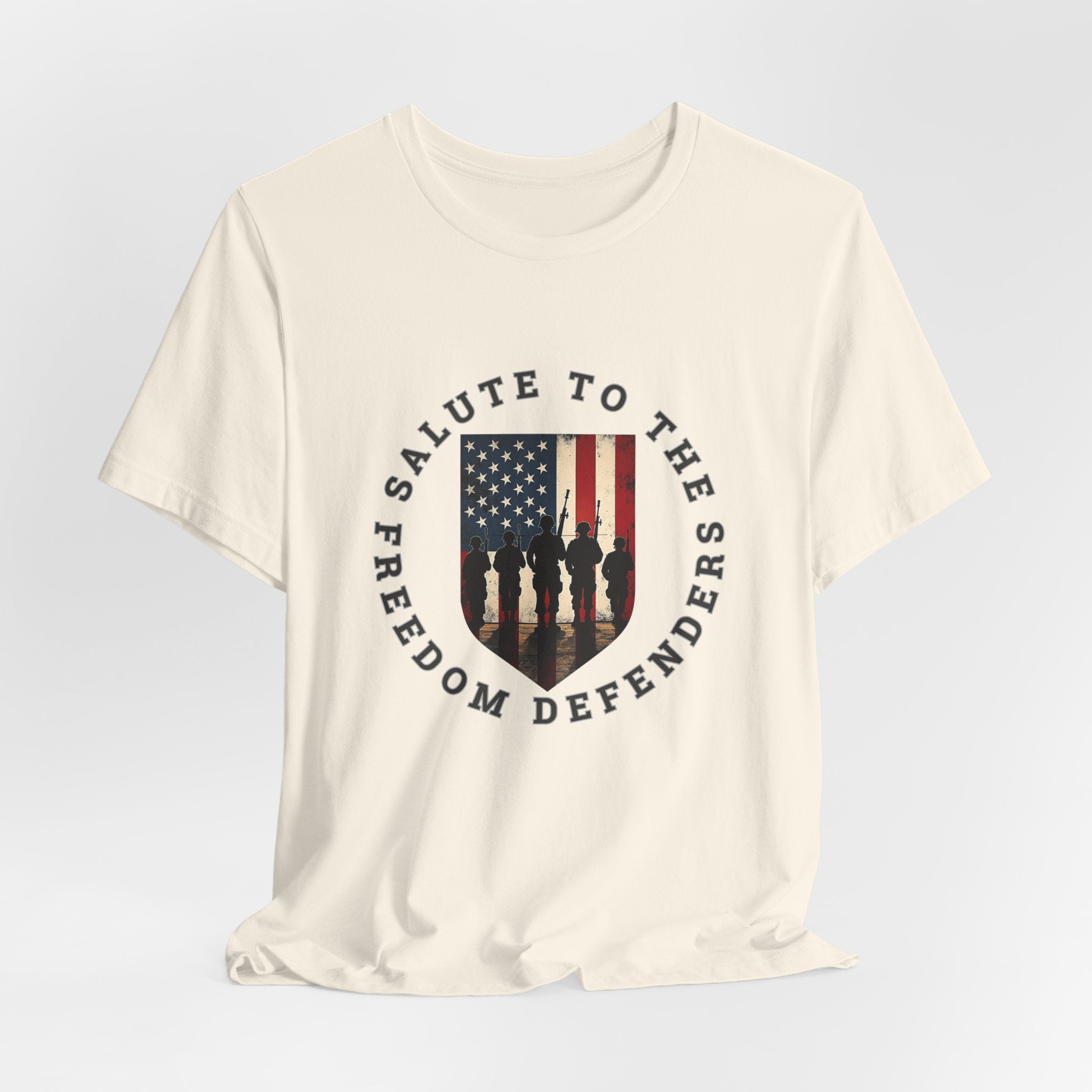 Ivory beige t-shirt with 'Salute to the Freedom Defenders' design featuring an American flag and silhouette of soldiers on a white background.