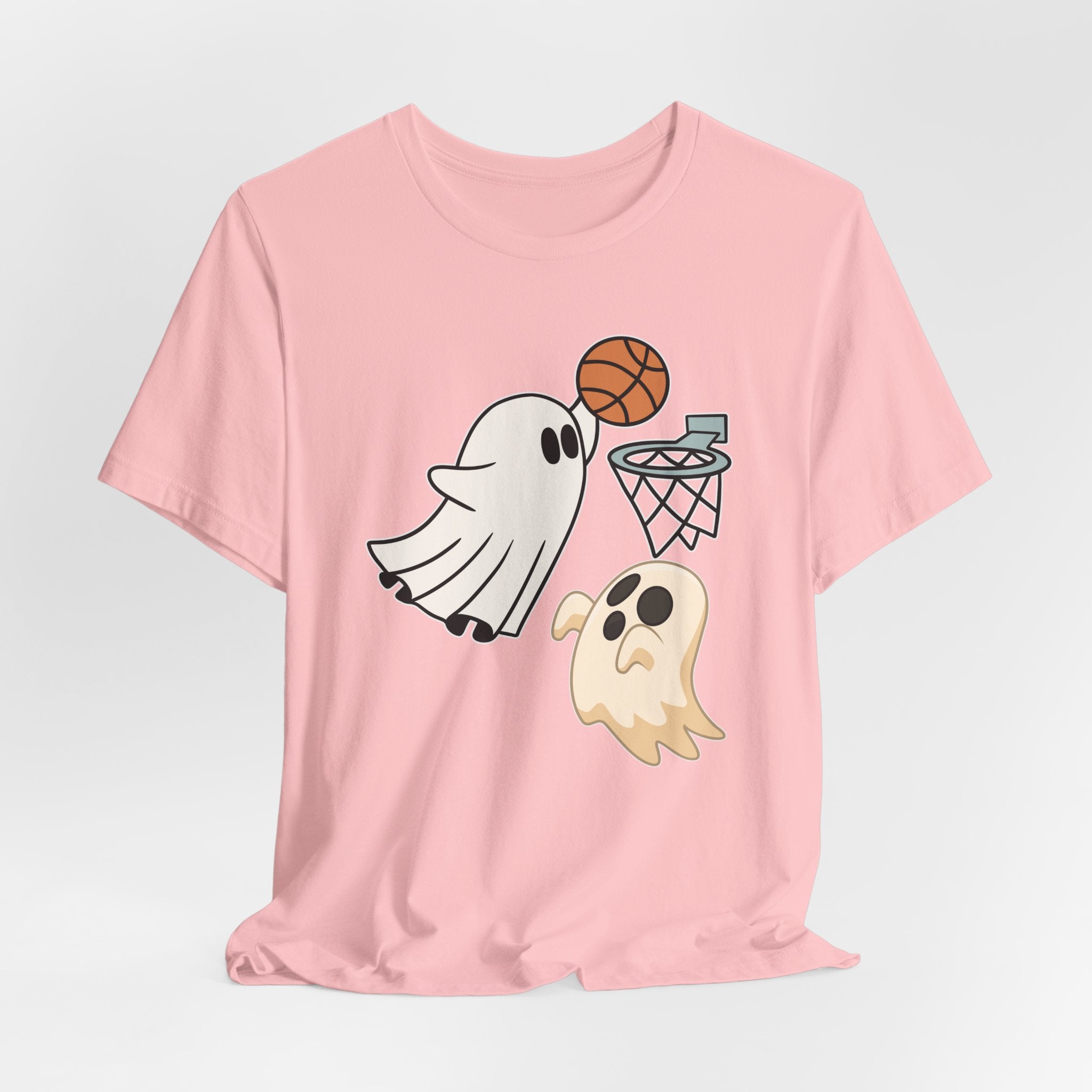 Pink t-shirt featuring cute spooky halloween ghosts playing basketball design on a white background