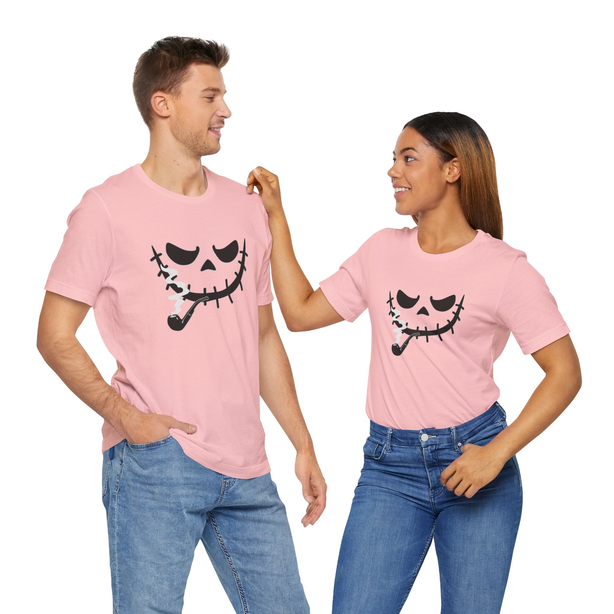 Two people wearing pink t-shirts with a black pumpkin face design on a white background
