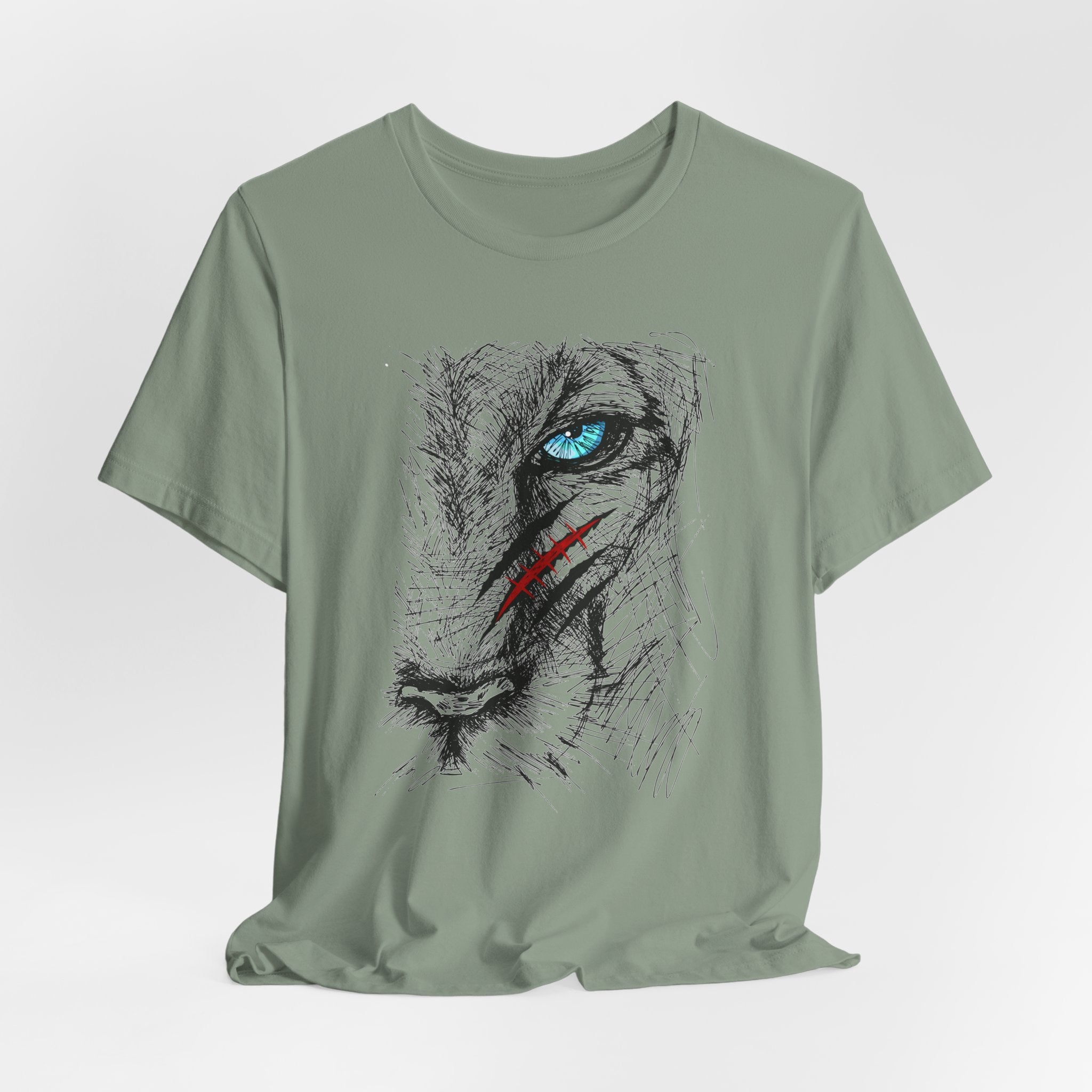 Sage green t-shirt with a graphic of a wounded lion's face with a blue eye