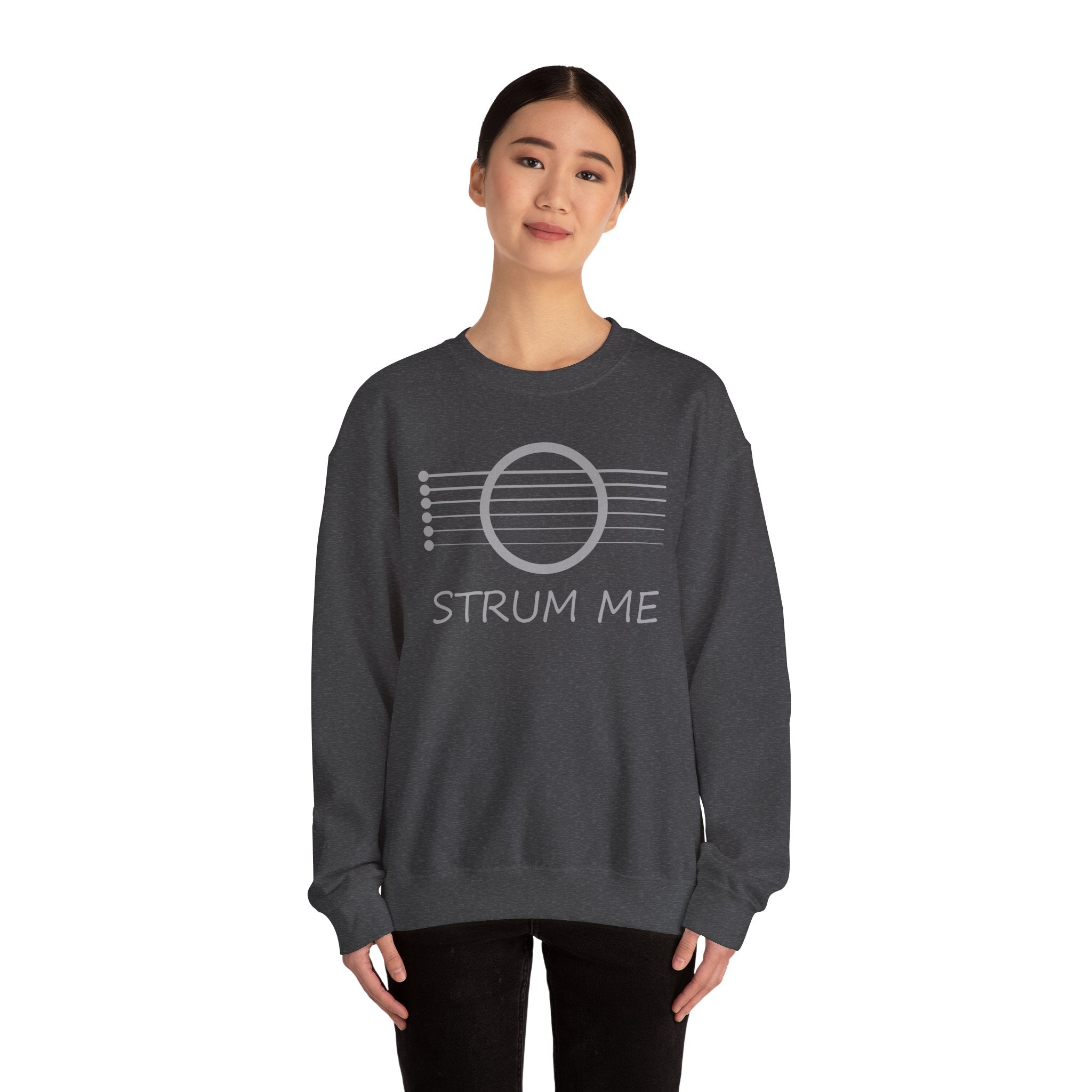A woman wearing gray sweatshirt sweatshirt with 'STRUM ME' text and acoustic guitar string design on a white background