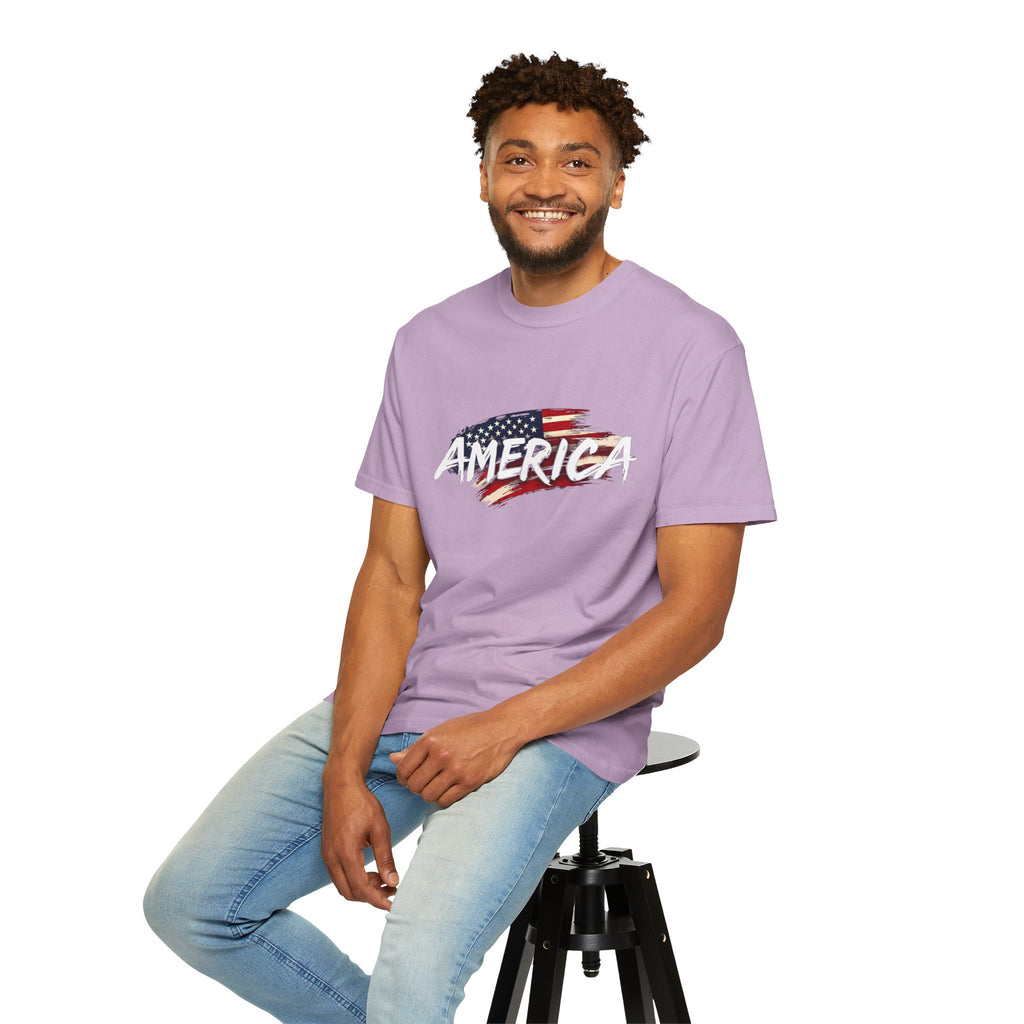 Man wearing a purple t-shirt with 'AMERICA' and an American flag design, sitting on a stool against a white background.