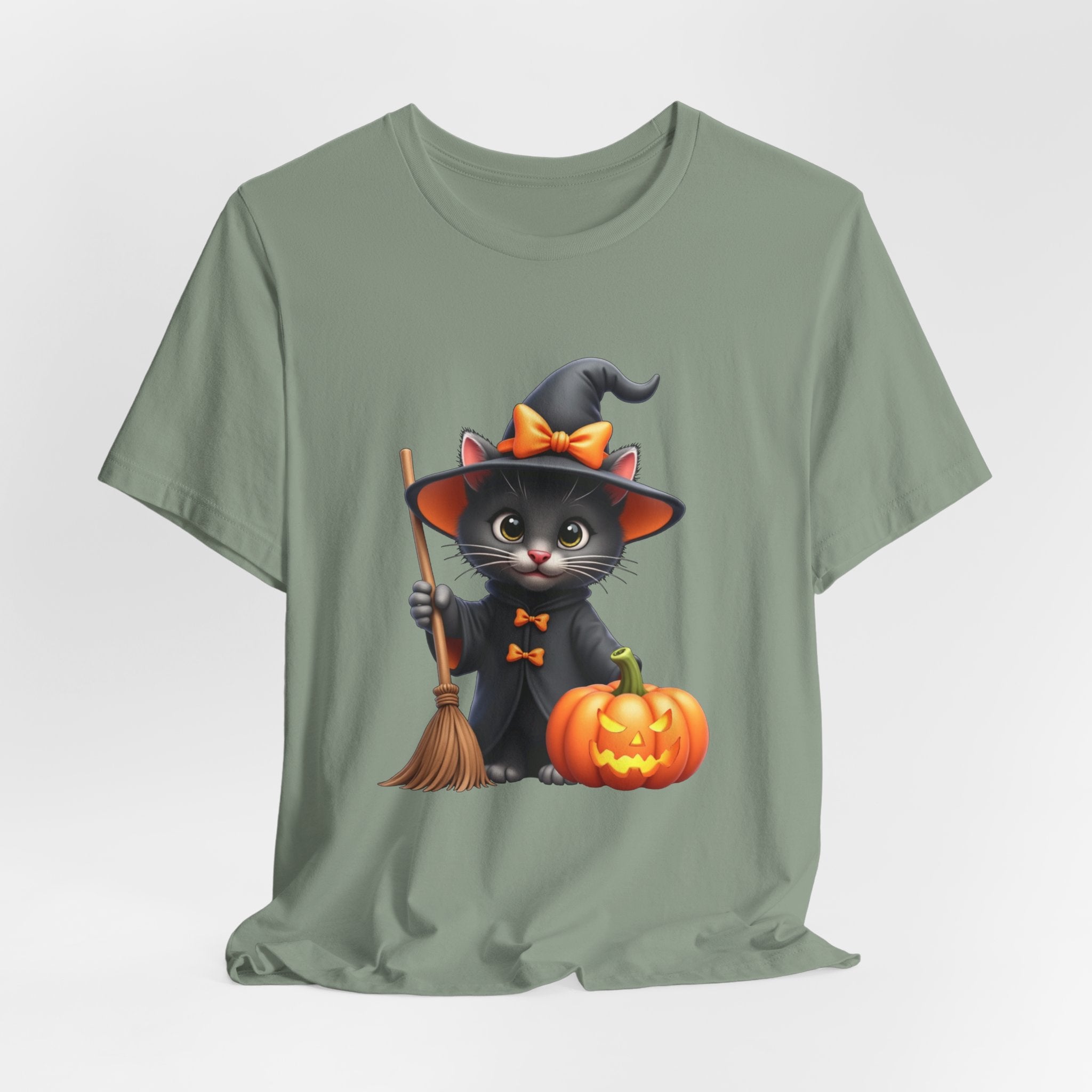 Sage green t-shirt with a Halloween-themed design of a cat in a witch costume, broom, and pumpkin on a light gray background.